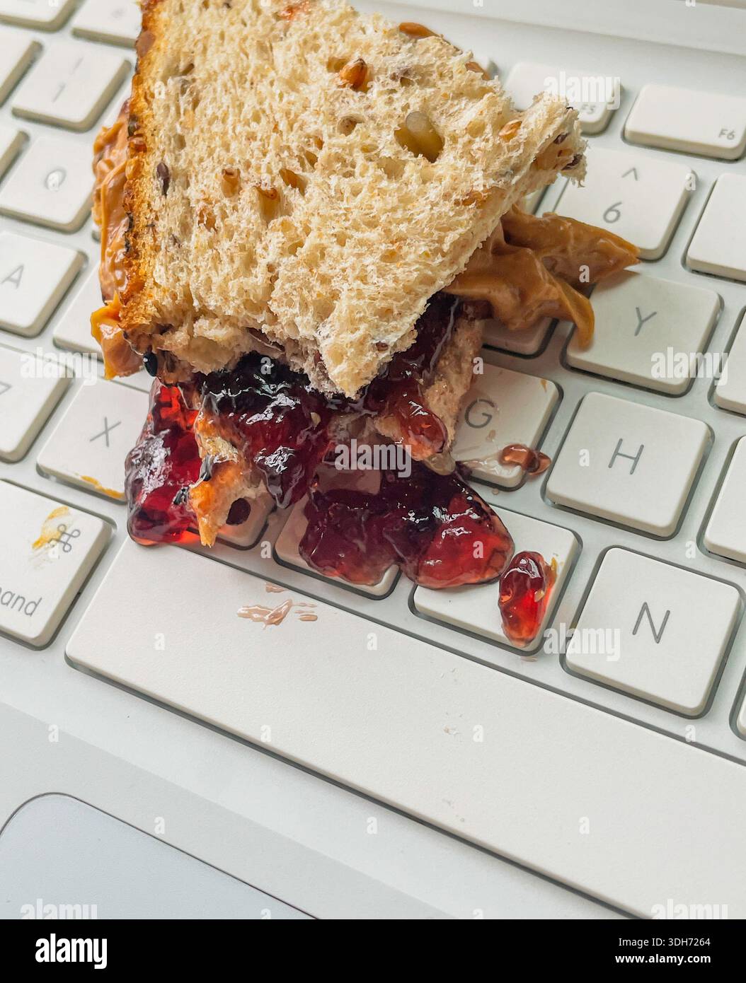 Primo piano di un sandwich di burro di arachidi e gelatina versato sulla tastiera di un computer, 2026, Stati Uniti - Immagine stock catturata con smartphone