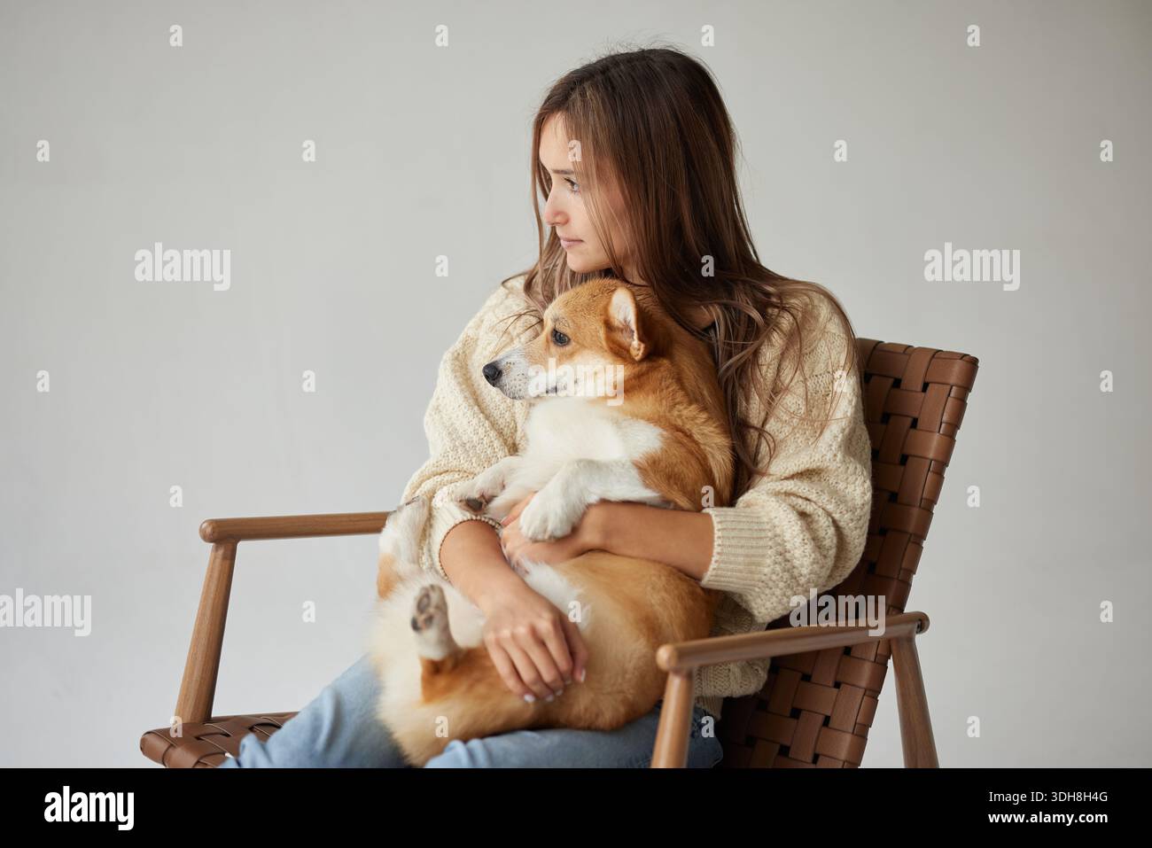 Intimo ritratto di una giovane donna che abbraccia il cane corgi sulla sedia, mostrando affetto comfort e compagnia con spazio fotocopie Foto Stock