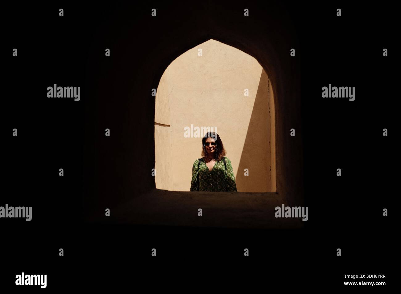 Una donna nella cornice di una finestra ad arco che si apre in una storica fortezza omanita a Nizwa Foto Stock
