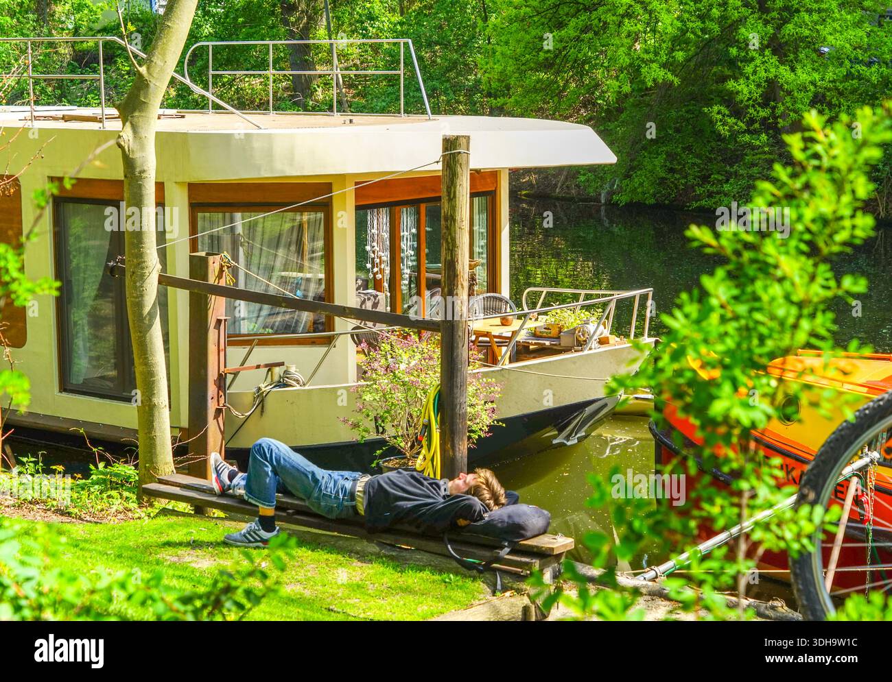Uomo rilassato che riposa di fronte alla sua casa galleggiante a Landwehrkanal, Berlino, Germania Foto Stock