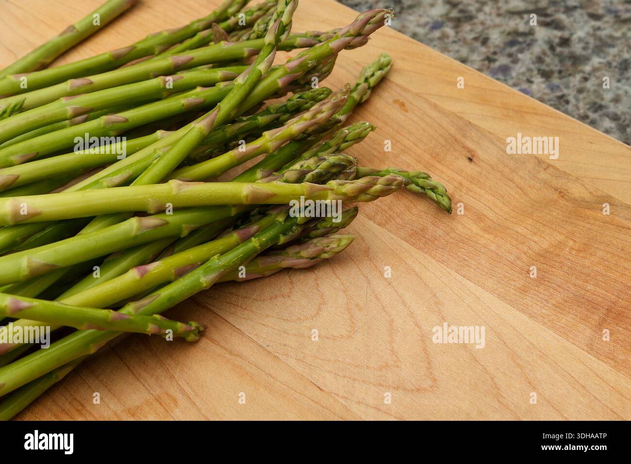 Primo piano di aste di asparagi fresche su tagliere in legno Foto Stock