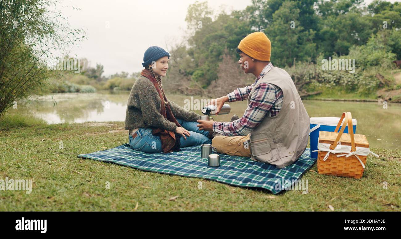 Felice, coppia e picnic con caffè all'aperto per viaggi, bevande calde e avventura di trekking. Sorridi, gente e campeggio con drink a colazione Foto Stock