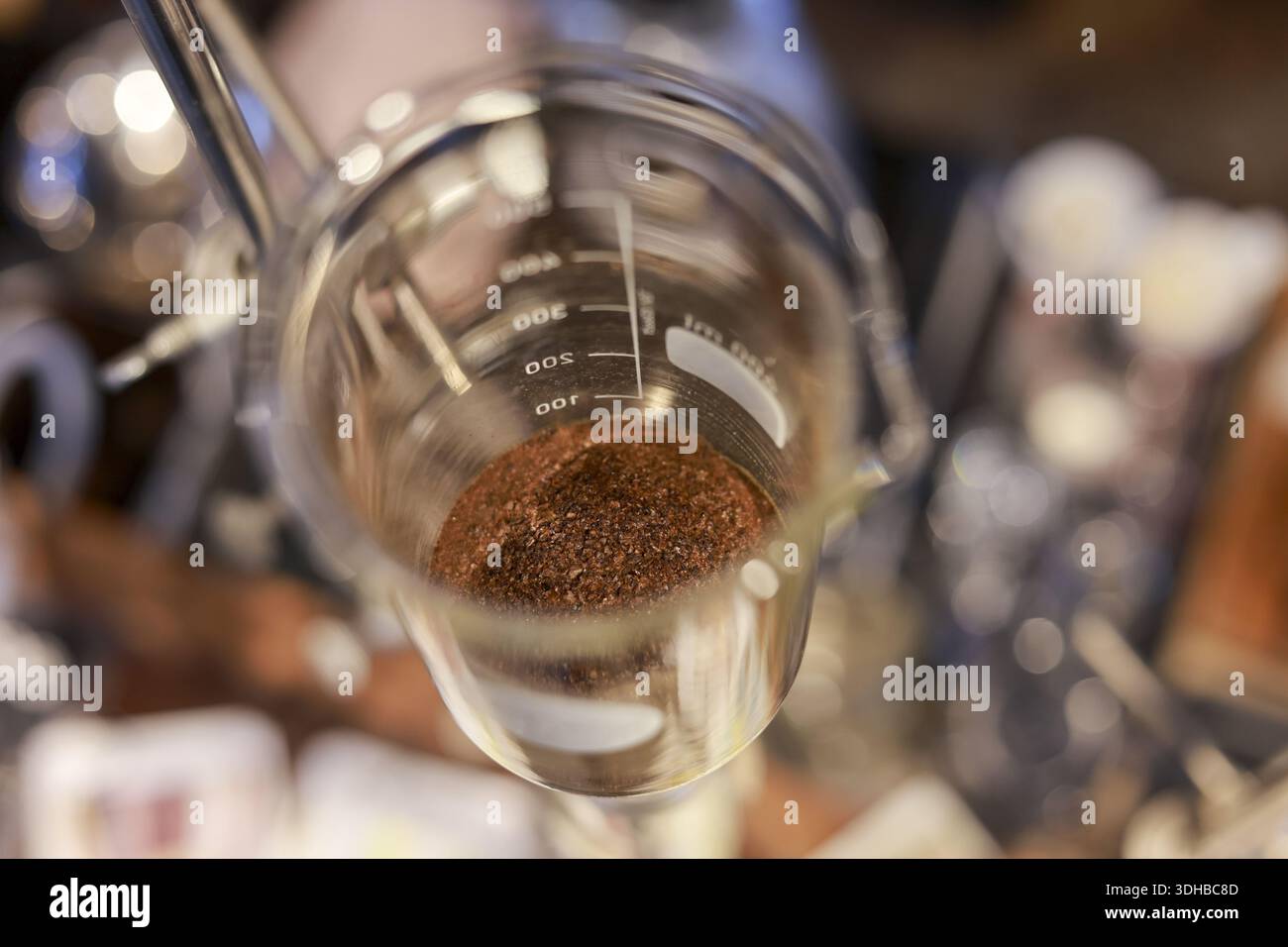 Vista dall'alto verso il basso del becher in vetro da laboratorio chimico contenente residui di polvere marrone che mostra un serio esperimento di ricerca scientifica con il misuru graduato Foto Stock