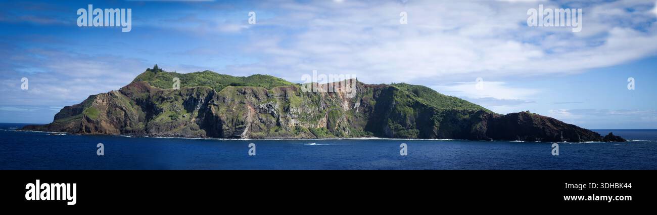 La vista di un'isola aspra con scogliere ripide e vegetazione lussureggiante sorge drammaticamente dal mare blu profondo, Adamstown, British Overseas Territory i Foto Stock