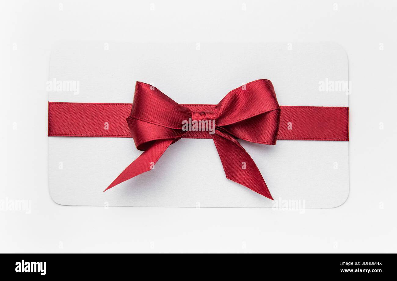 Modello di carta regalo bianca con un nastro in raso rosso legato a un fiocco Foto Stock