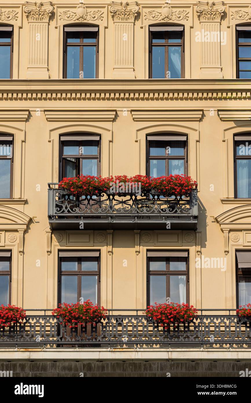 Storica facciata gialla con balcone e fiori di geranio a Stoccolma, Svezia, ideale per paesaggi urbani, viaggi e temi architettonici svedesi. Foto Stock