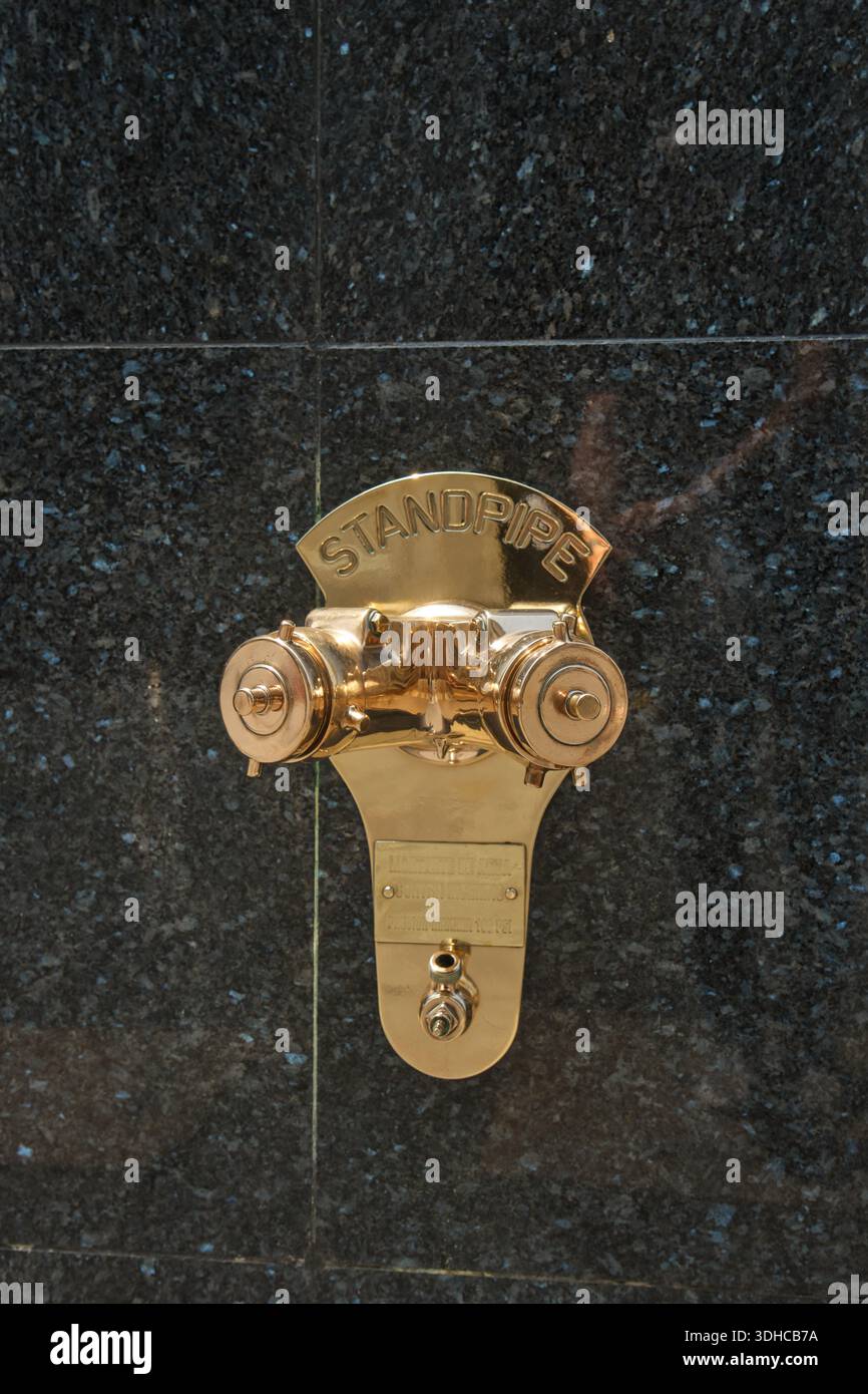 Lima, Perù. 16 gennaio 2026, raccordo tubo standard in ottone che fornisce protezione antincendio su una parete di granito scuro Foto Stock