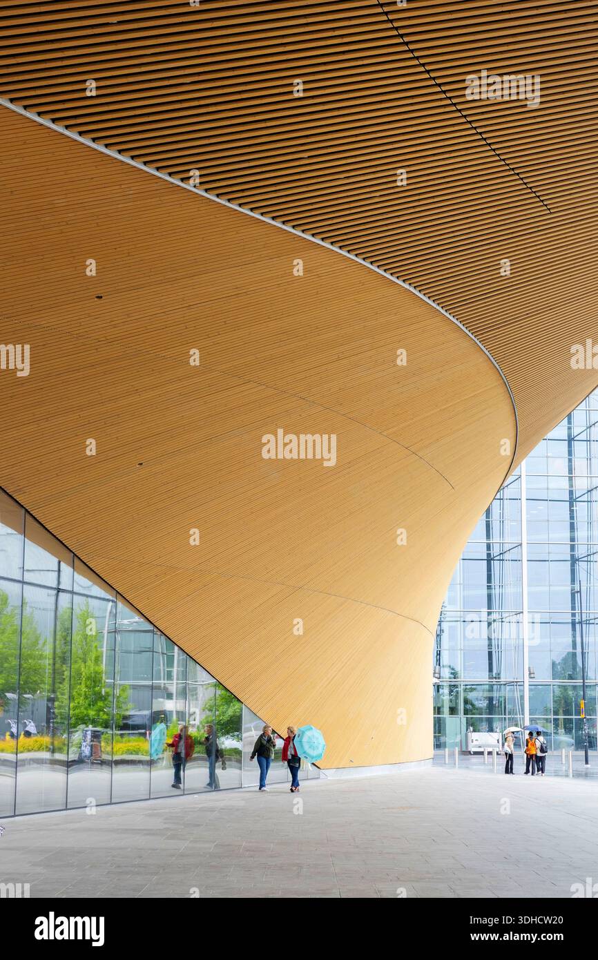 Finlandia, Helsinki, biblioteca centrale, donne con ombrello che passano davanti all'edificio in legno Foto Stock