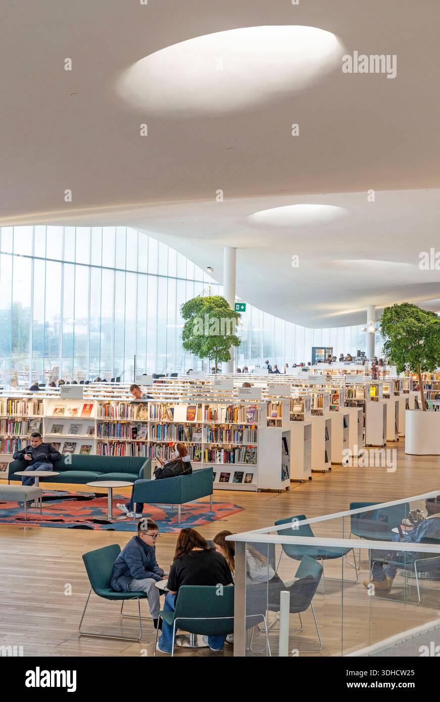 Finlandia, Helsinki, biblioteca centrale, persone sedute negli interni luminosi con il suo elegante design bianco Foto Stock