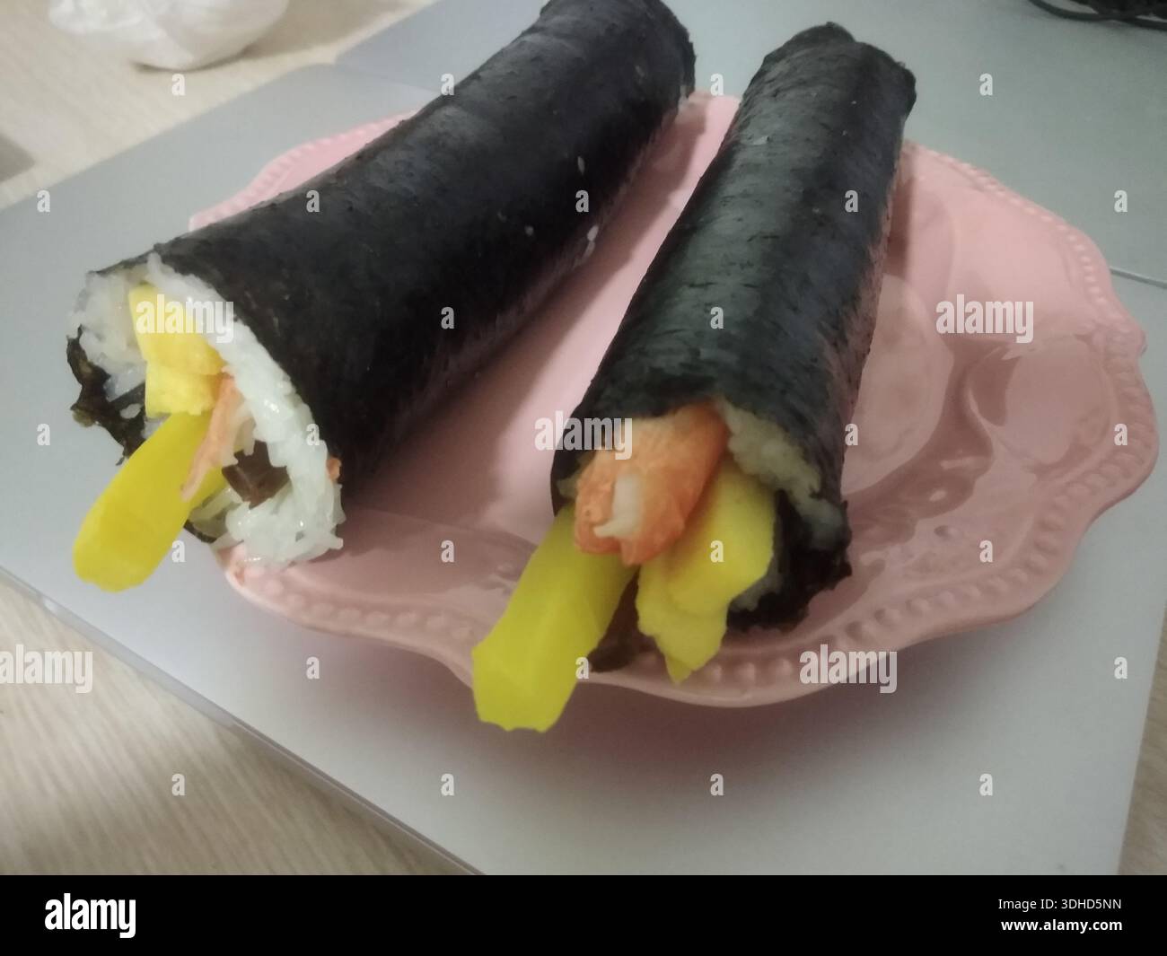 Due rotoli di kimbap giapponesi su piatto rosa Foto Stock