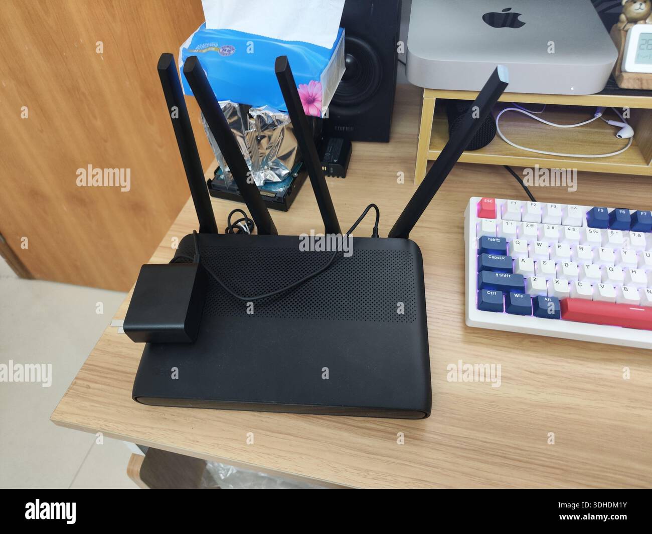 Router wireless con antenne su una scrivania accanto alla tastiera meccanica Foto Stock