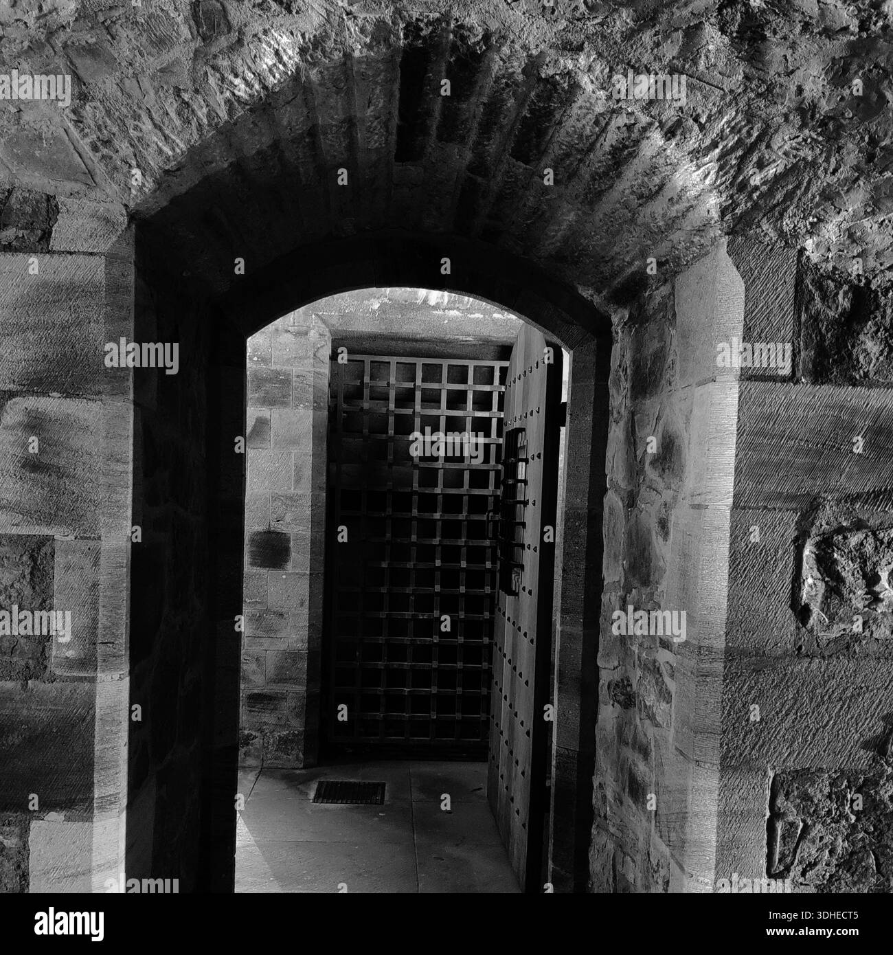 Antica arcata in pietra che conduce ad una porta medievale a grata di ferro Foto Stock