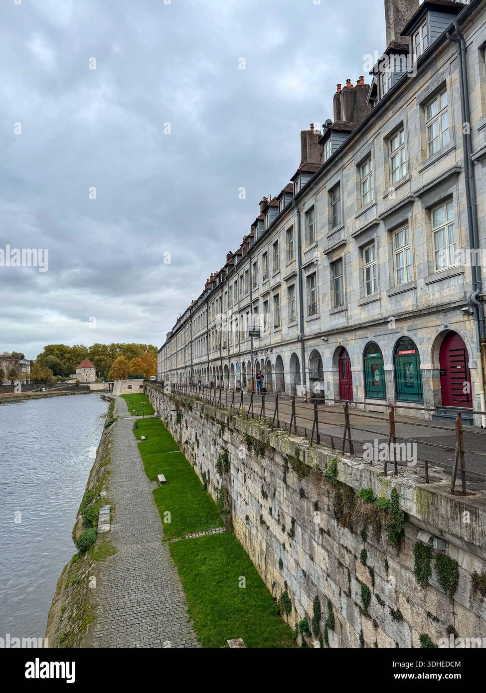 edifici storici in pietra e banchina lungo il fiume doubs a besancon, francia. l'immagine mostra l'architettura tradizionale con porte ad arco - Immagine stock catturata con smartphone