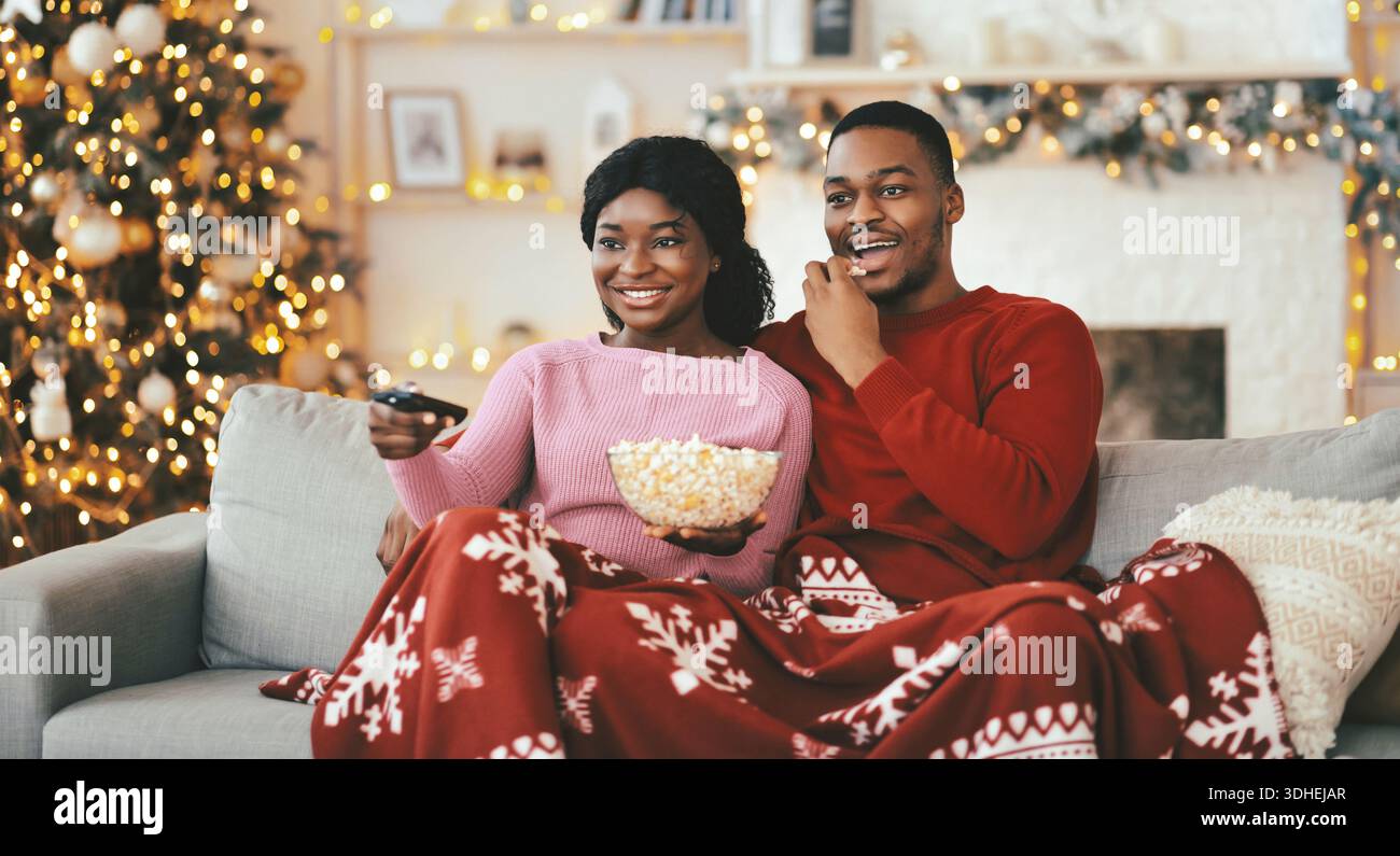La coppia si diverte a una serata al cinema con popcorn sul divano durante la stagione invernale Foto Stock
