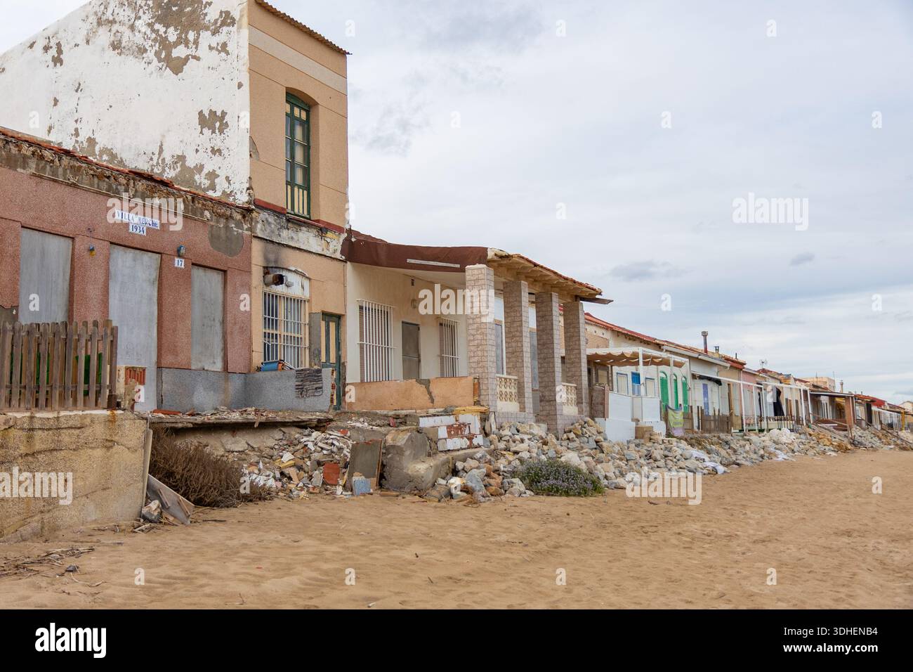 Alicante, Spagna - 17 gennaio 2026: Una fila di case sulla spiaggia battute dal tempo, le Casas de Babilonia, case di Babilonia si erge direttamente sulla spiaggia sabbiosa Foto Stock