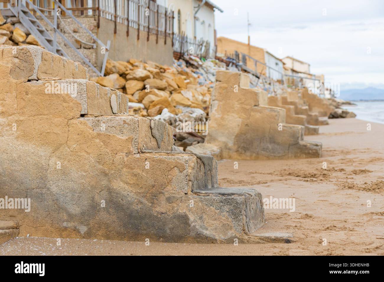 Alicante, Spagna - 17 gennaio 2026: Una fila di case sulla spiaggia battute dal tempo, le Casas de Babilonia, case di Babilonia si erge direttamente sulla spiaggia sabbiosa Foto Stock