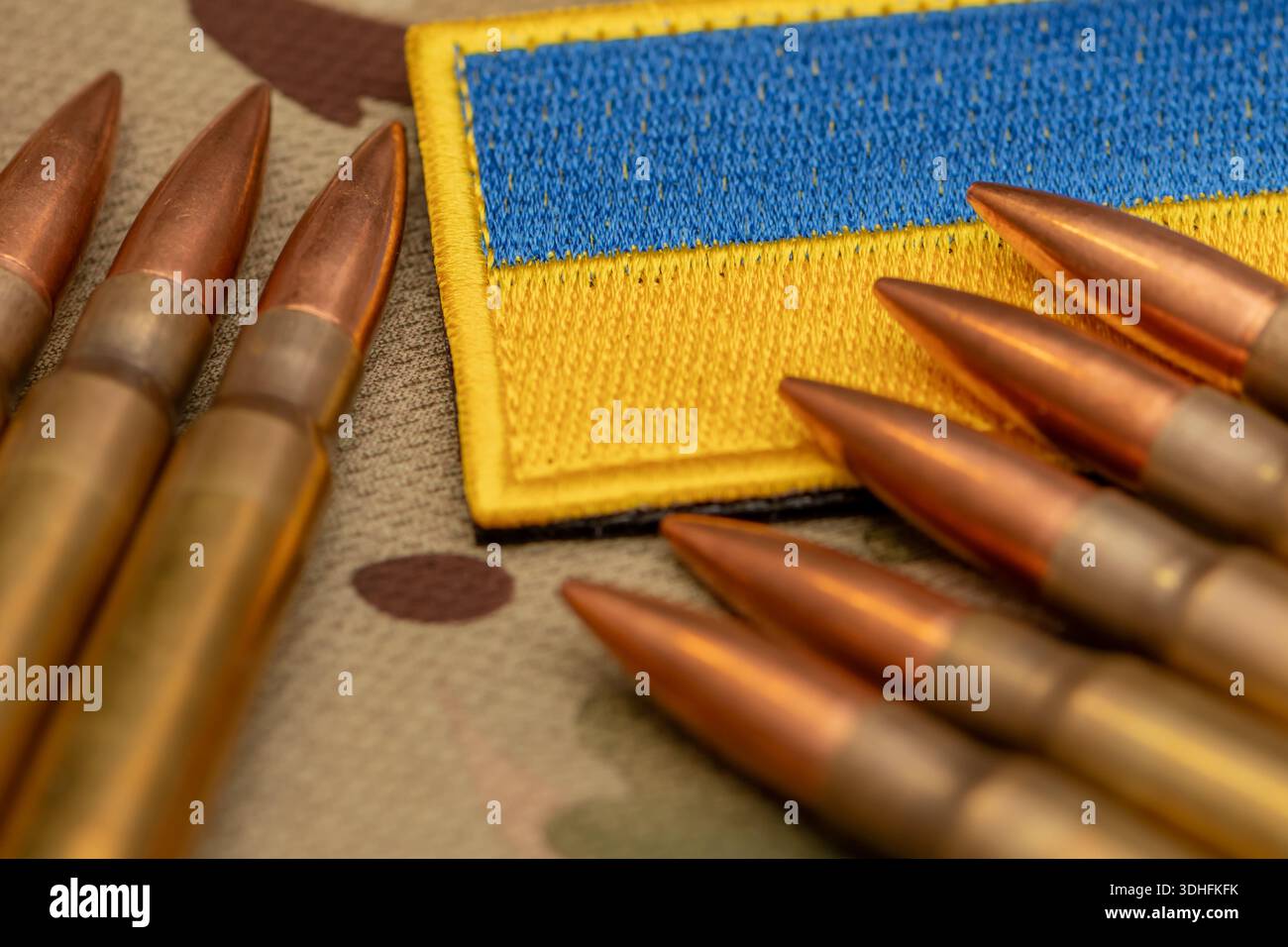 Munizioni disposte intorno alla patch di bandiera Ucraina su tessuto militare mimetico Foto Stock