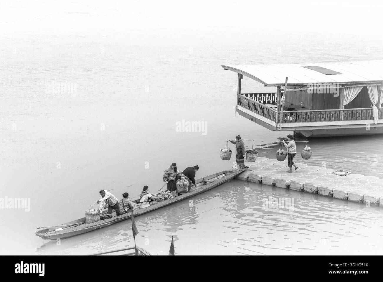 I venditori di donne laotiane salgono a bordo di un piccolo traghetto presso un molo galleggiante sul fiume Mekong con cesti di riso appiccicoso per dare le elemosine buddiste, il Laos Foto Stock