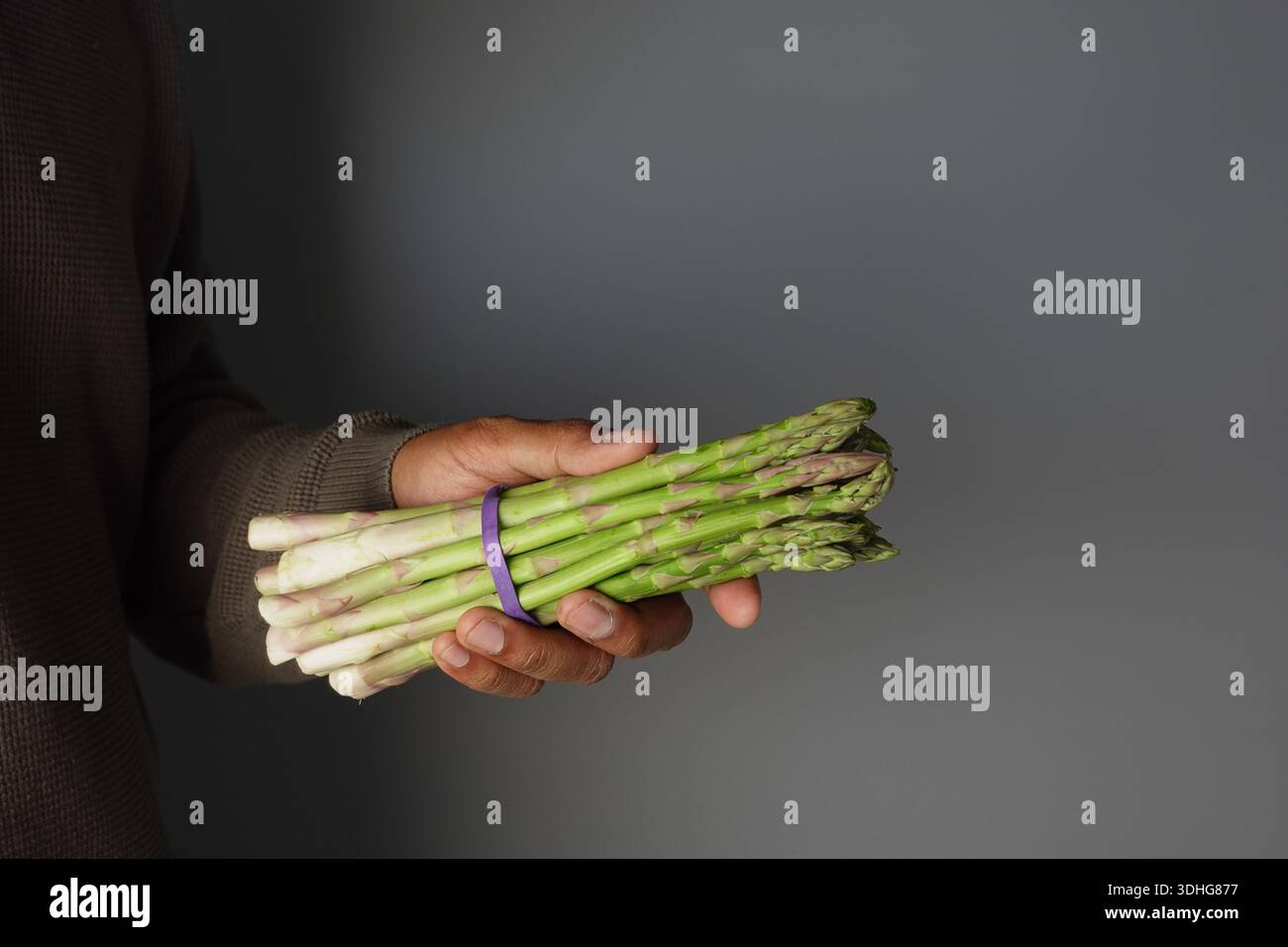 Persona che tiene in mano un fascio di asparagi verdi Foto Stock