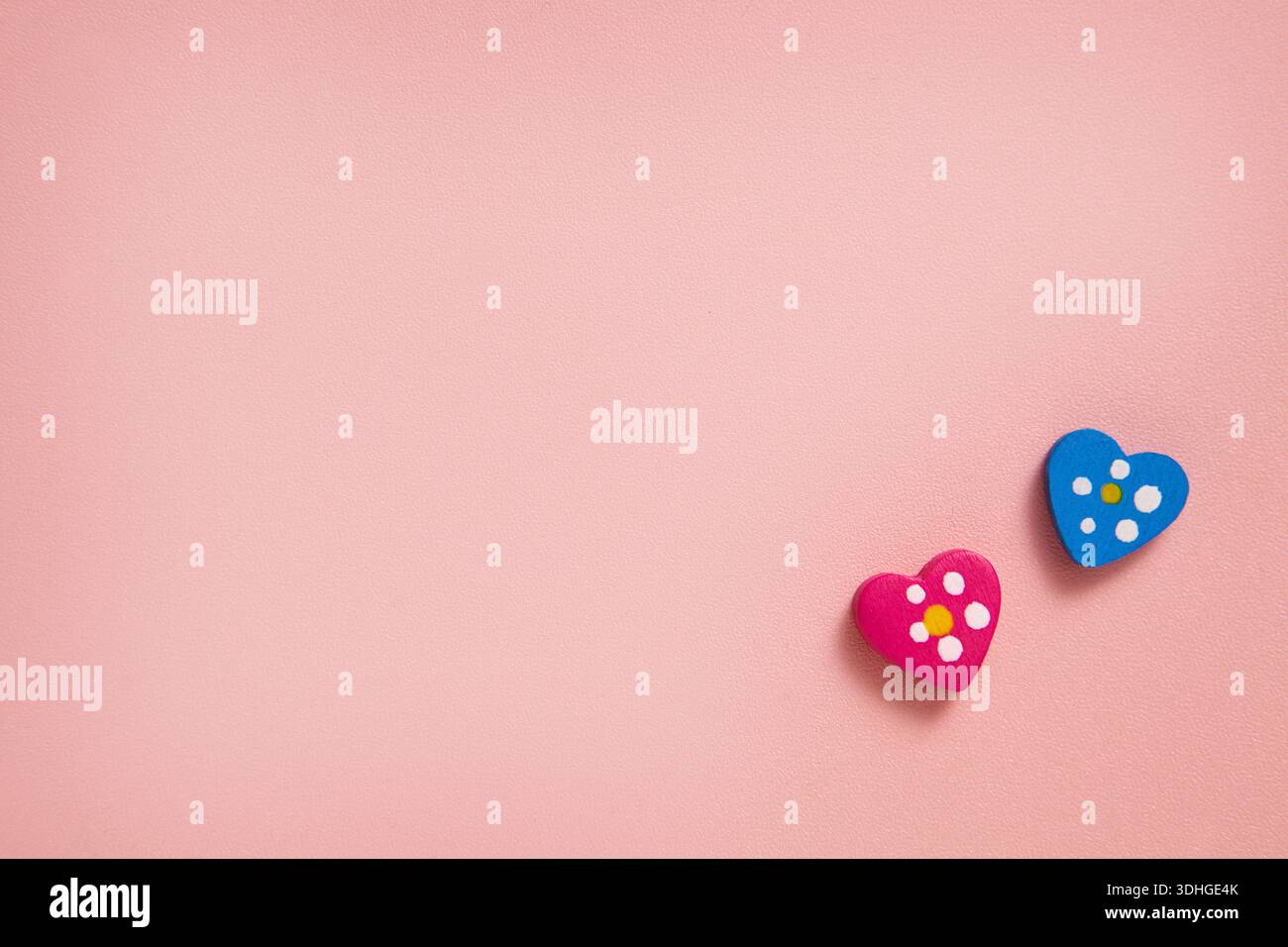 Una foto minimalista con due piccole decorazioni a forma di cuore su un delicato sfondo rosa, che creano un'atmosfera dolce e romantica. Per biglietti d'auguri Foto Stock