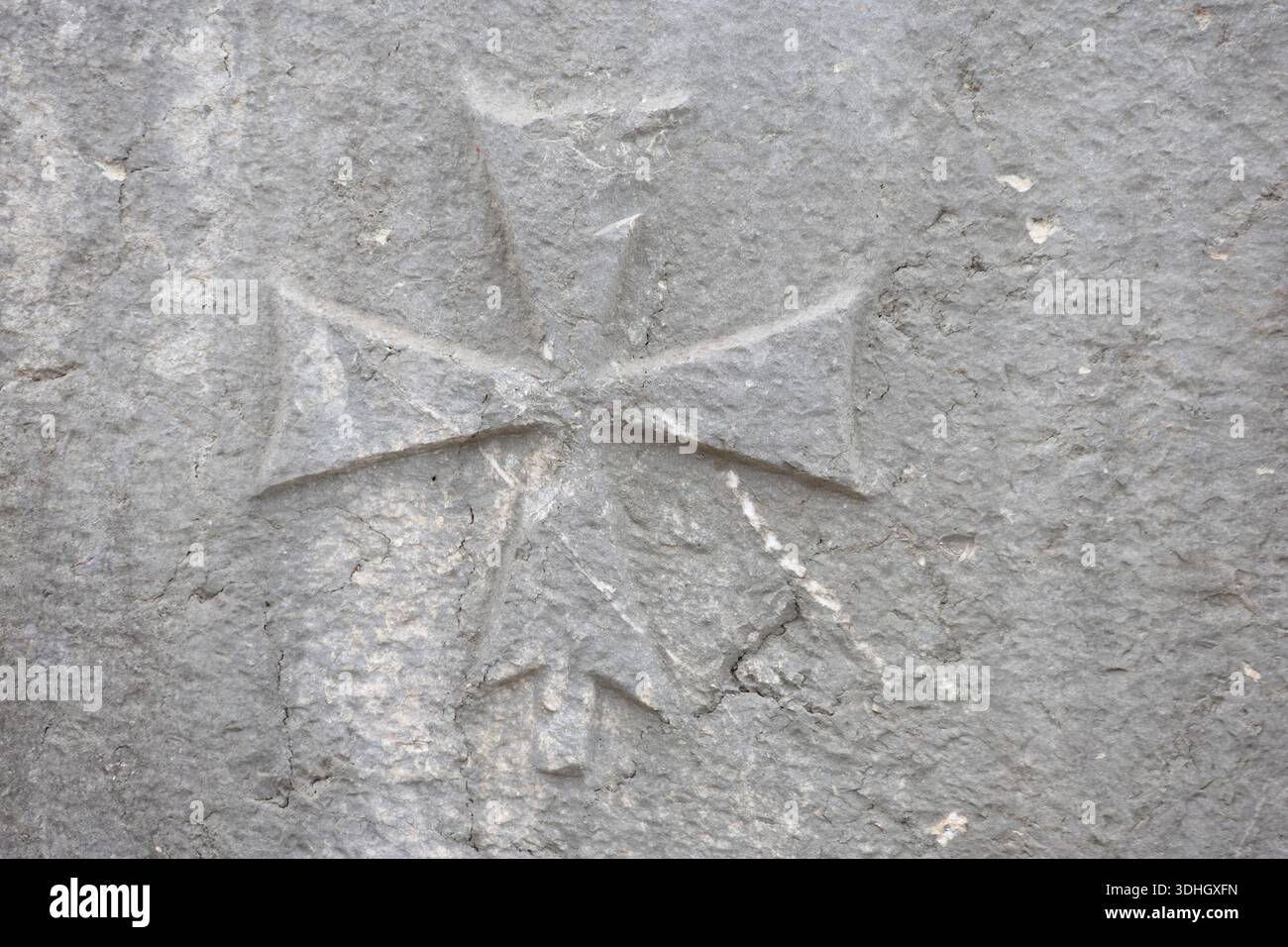 Antico monumento a croce di pietra intemprata in mezzo alle pareti di roccia sbriciolate di una chiesa in rovina sui monti Aladağlar Foto Stock