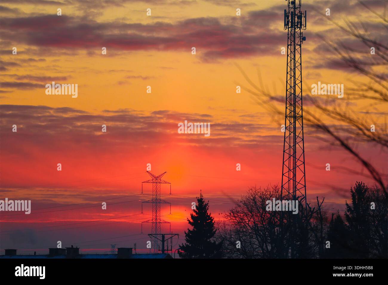 Fiery Sunrise Sky con Torre di comunicazione e linee elettriche Foto Stock