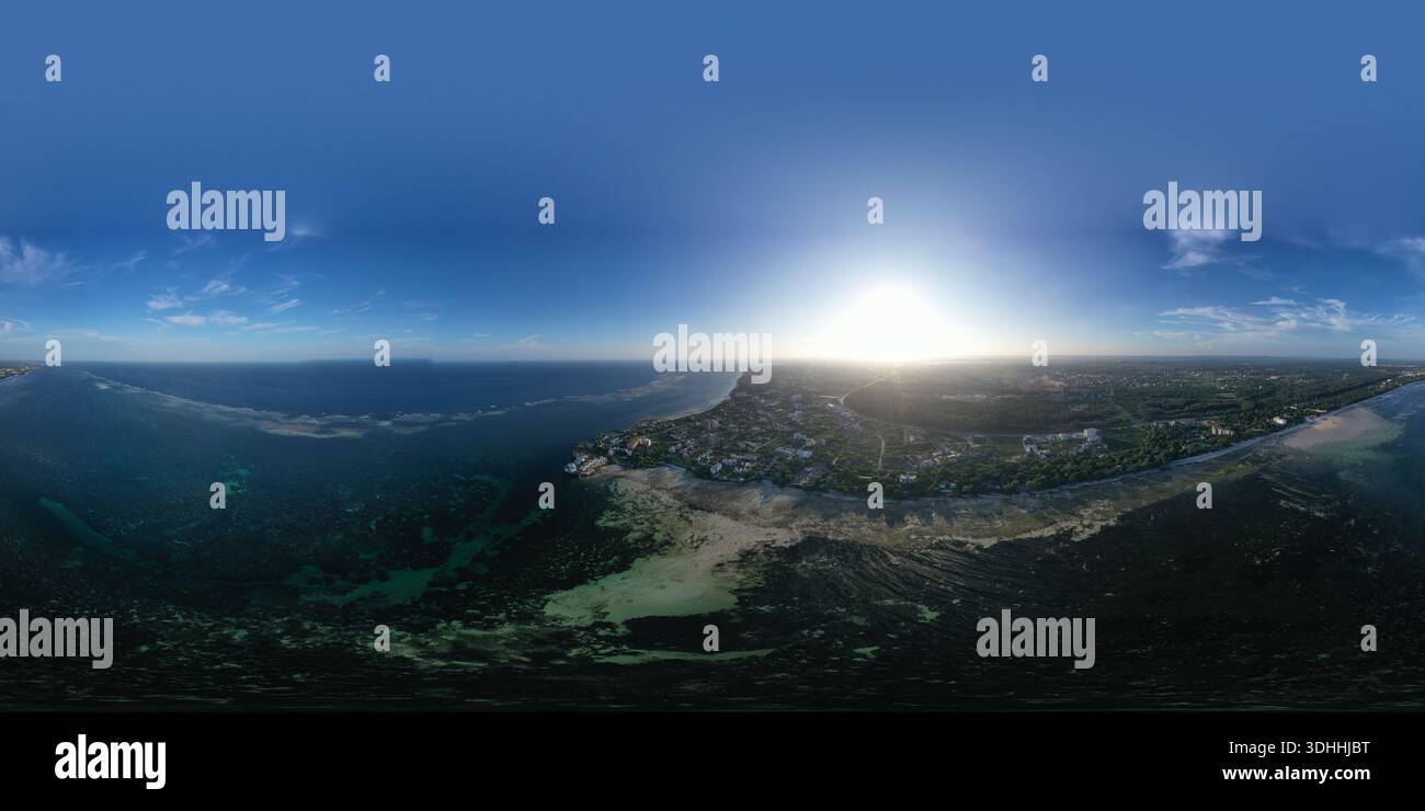 Vista aerea delle coste baciate dal sole che incontrano il mare blu profondo, con edifici annidati tra la vegetazione verde, Mombasa, Kenya. Foto Stock