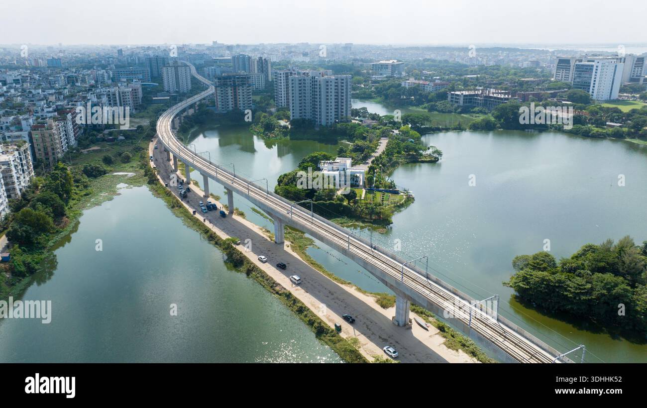 Veduta aerea di dia Bari Road, dove la linea sopraelevata della metropolitana taglia il paesaggio, riflettendo nell'acqua, Dacca, Divisione di Dacca, Bangladesh. Foto Stock