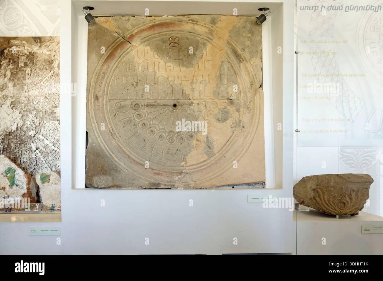 Antica meridiana in pietra armena con iscrizioni esposte in una galleria museale accanto a manufatti storici Foto Stock