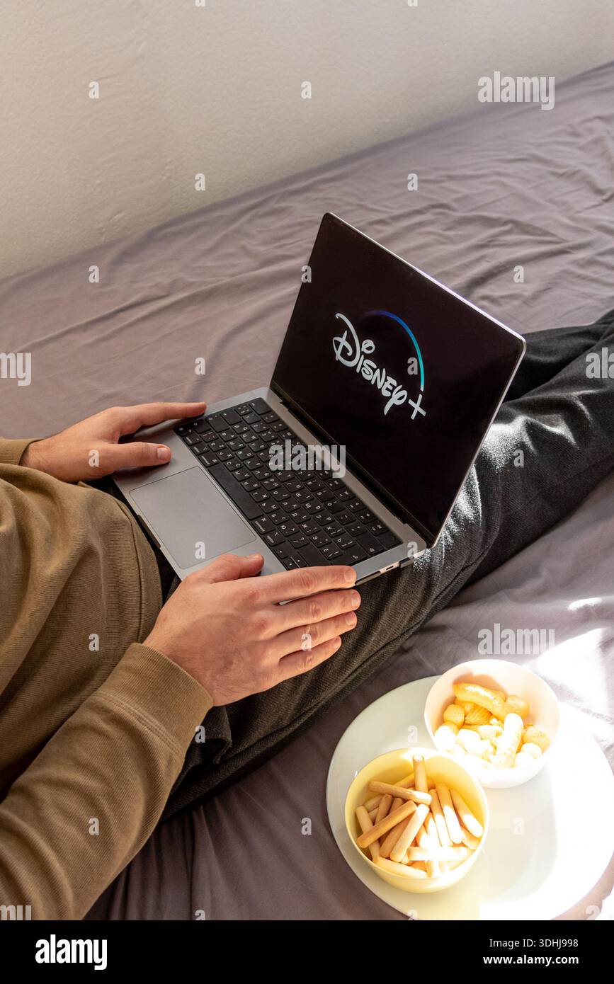 Bar, Montenegro, 22 gennaio 2026, uomo che guarda un film sulla piattaforma Disney Plus sul computer portatile seduto sul letto di casa Foto Stock