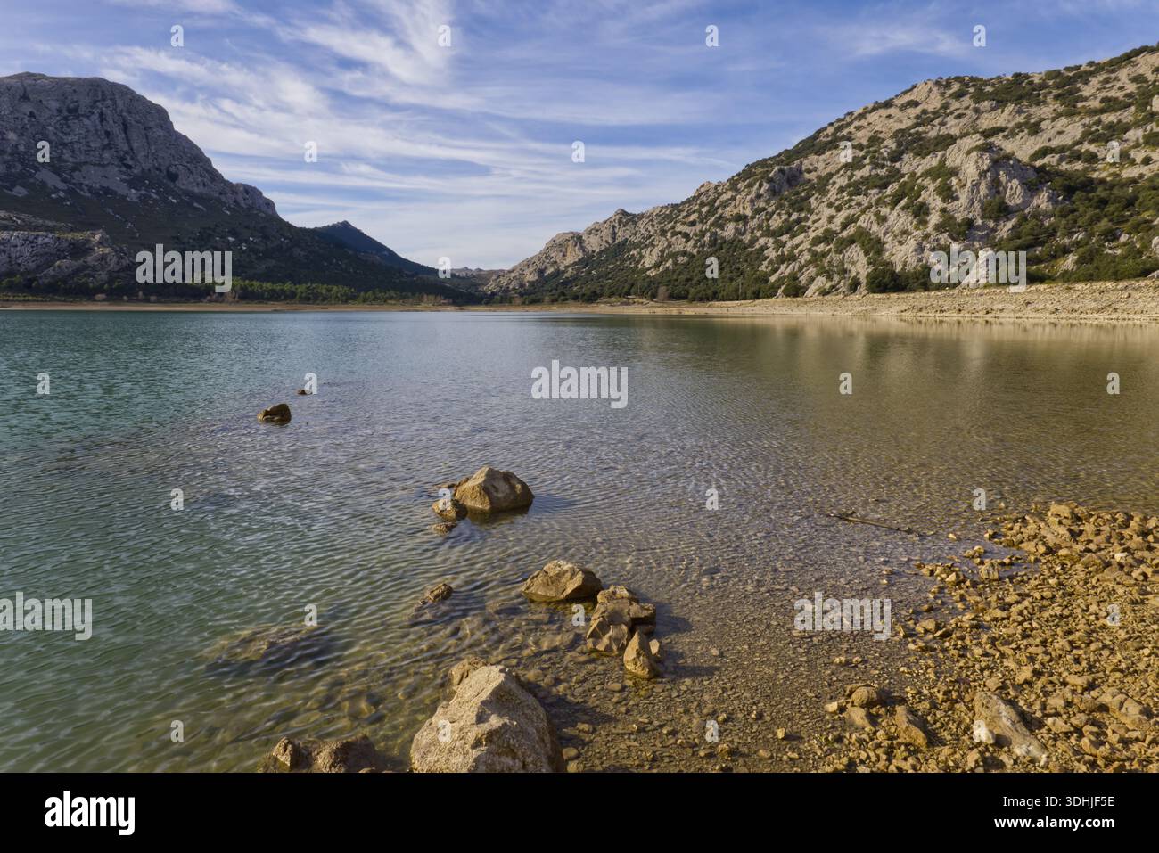 Pietre sul litorale del bacino idrico di Cúber nelle montagne della Serra de Tramuntana, Maiorca, sotto un cielo blu con nuvole. Foto Stock