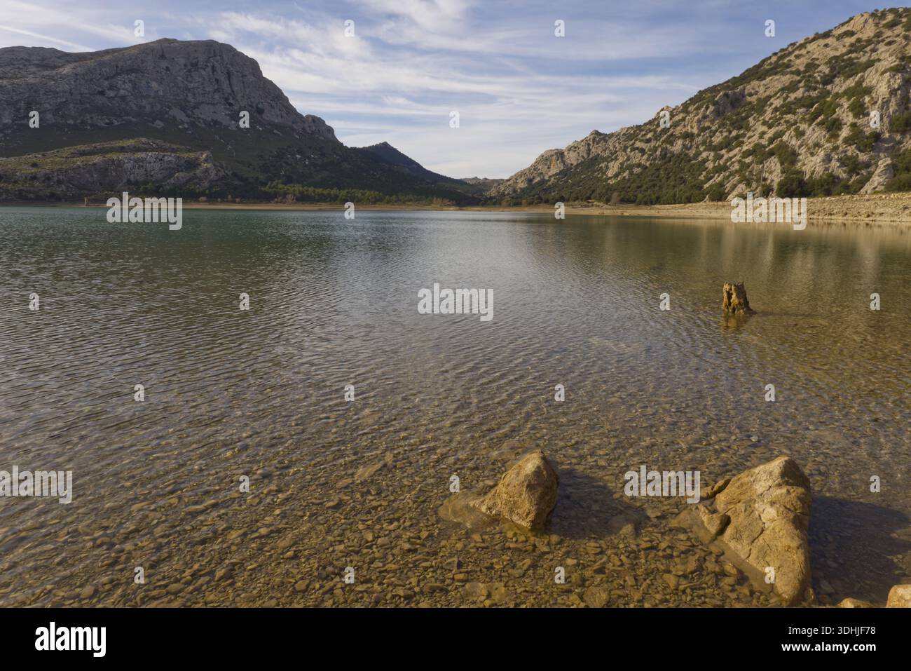 Pietre sul litorale del bacino idrico di Cúber nelle montagne della Serra de Tramuntana, Maiorca, sotto un cielo blu con nuvole. Foto Stock