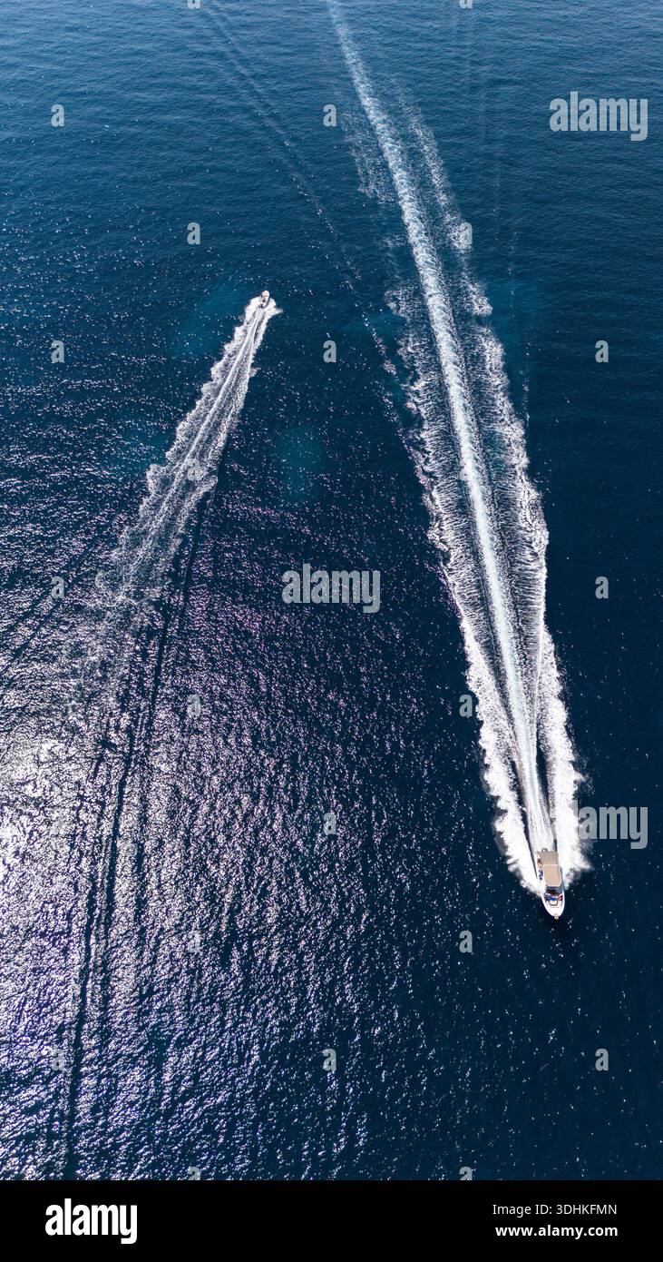 Vista aerea di due barche che attraversano il mare blu profondo, lasciando sentieri bianchi e spumeggianti che contrastano nettamente con le acque azzurre della Spagna. Foto Stock