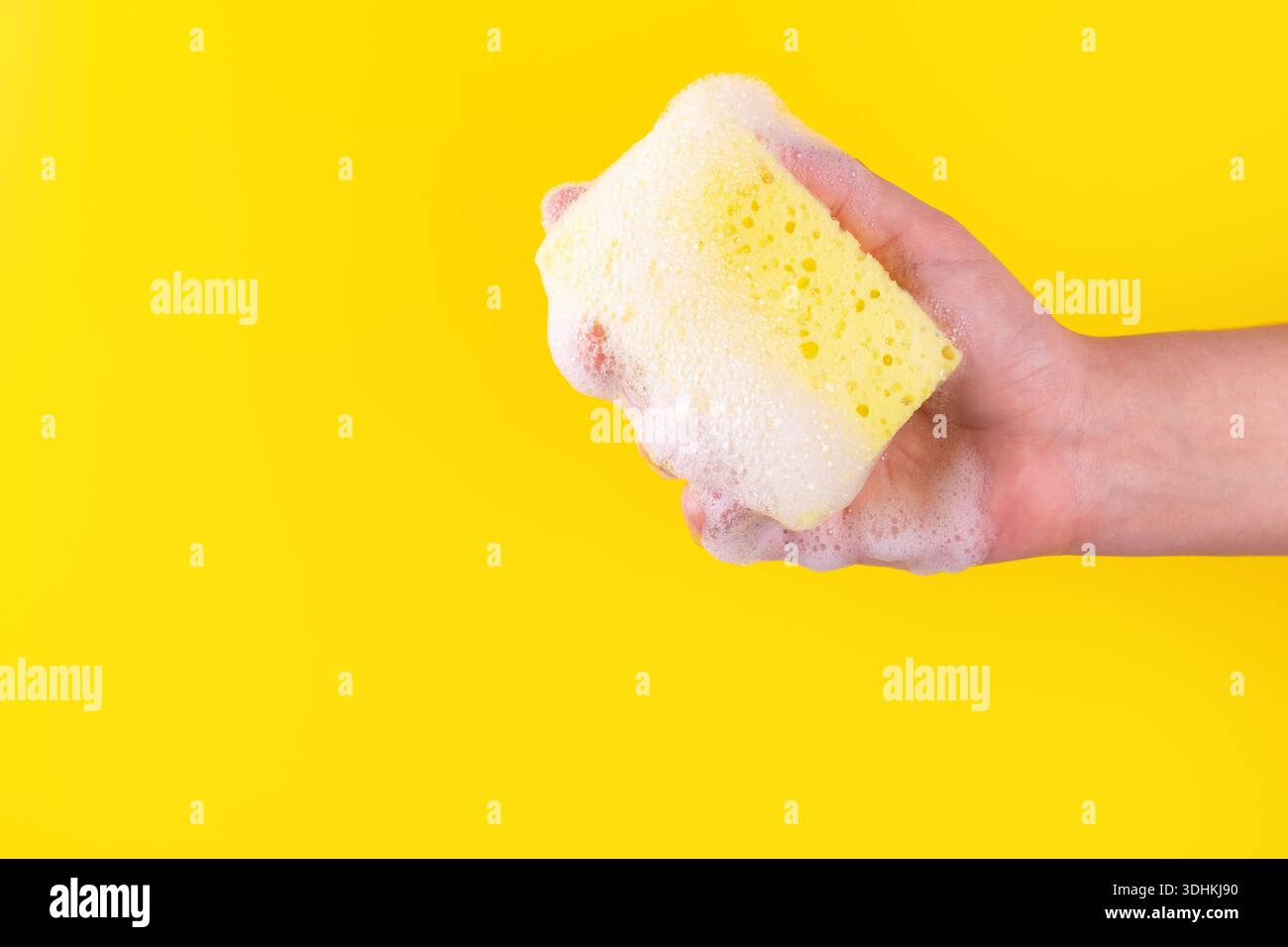Persone che tengono la spugna gialla per lavare i piatti. Panno imbevuto di sapone. Concetto di lavori domestici e forniture. Detergente per piatti sensibile. Co Foto Stock