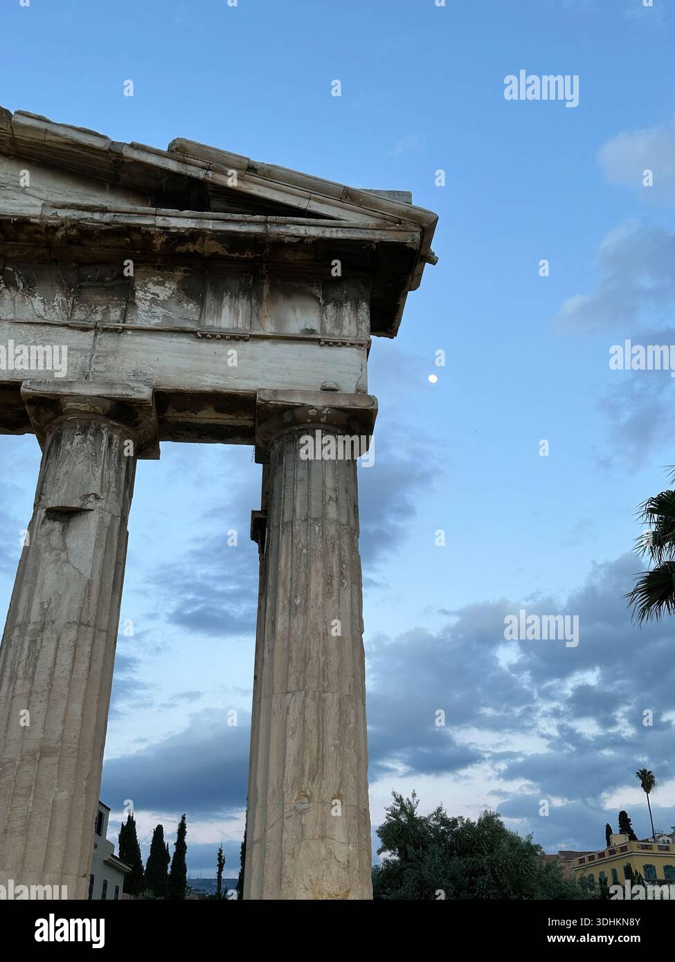 Antiche colonne in pietra classica contro un cielo crepuscolo con la luna visibile, rovine storiche e concetto di patrimonio culturale. Foto Stock