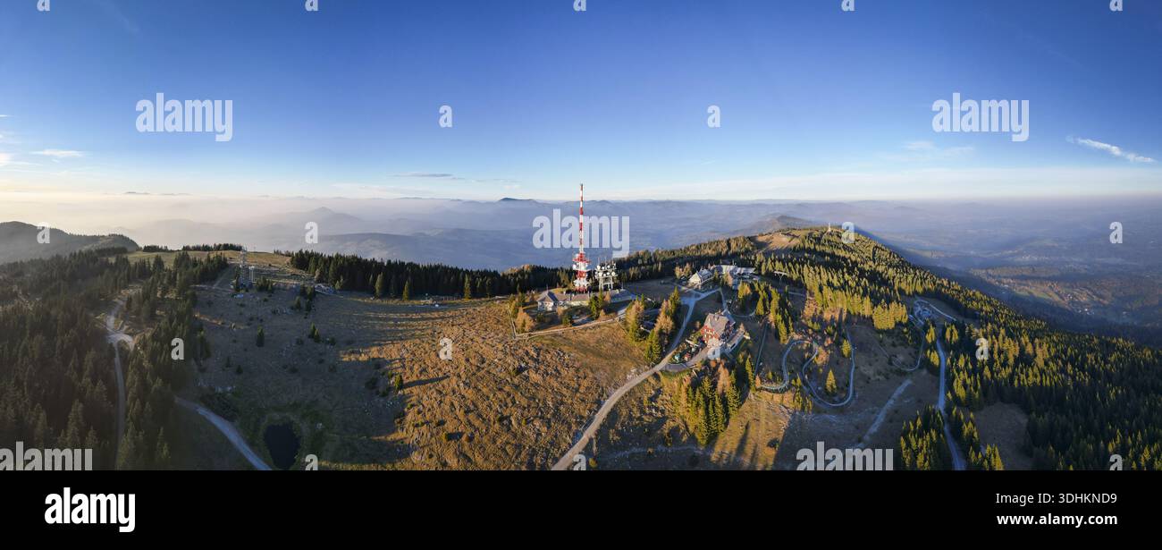Veduta aerea di una torre rossa e bianca che penetra nella fresca aria mattutina sopra il monte Schöckl, Graz, Stiria, Austria. Foto Stock
