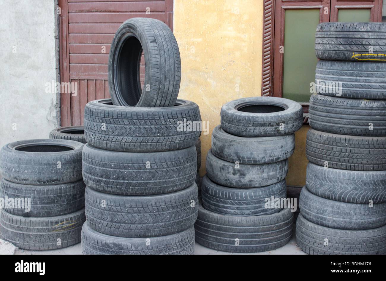 Vecchi pneumatici in attesa di essere riutilizzati. Pile di vecchie gomme per auto a terra. Foto Stock