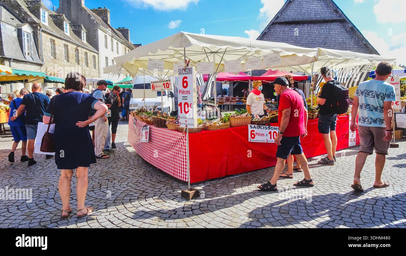 Vivace mercato acciottolato con numerose bancarelle e persone sotto ombrelli colorati, pieno di attività vivace. Foto Stock