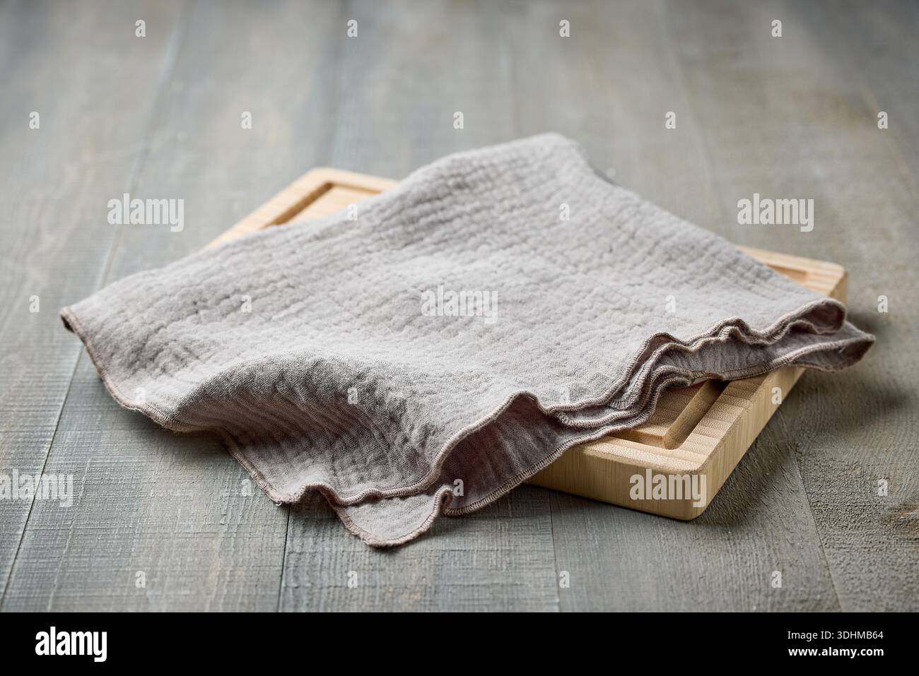 tagliere in legno e tovagliolo in lino su fondo rustico Foto Stock