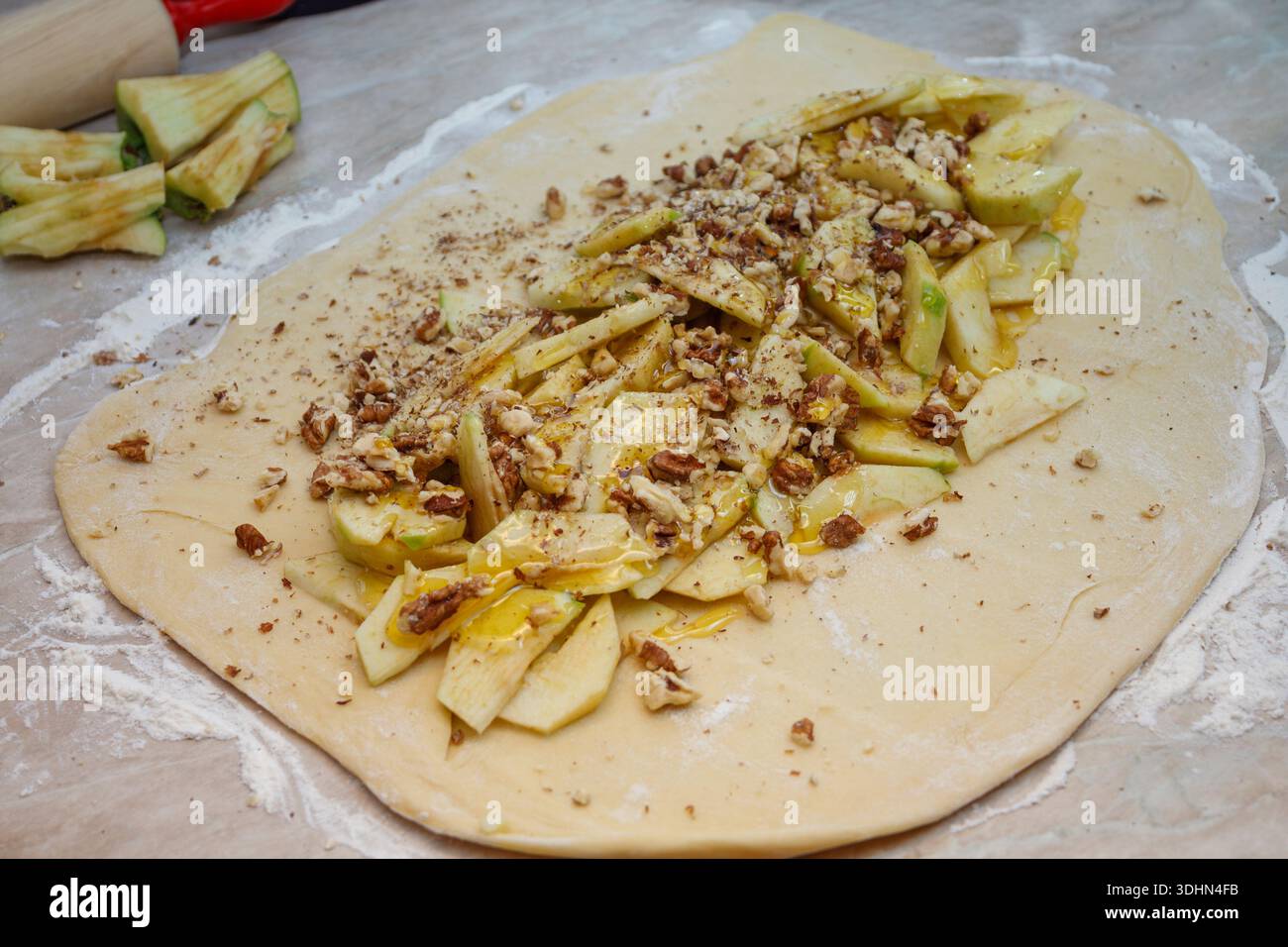 Impasto di lievito crudo stappato con ripieno di mele e noci. Preparazione di torte intrecciate dolci fatte in casa. Foto Stock