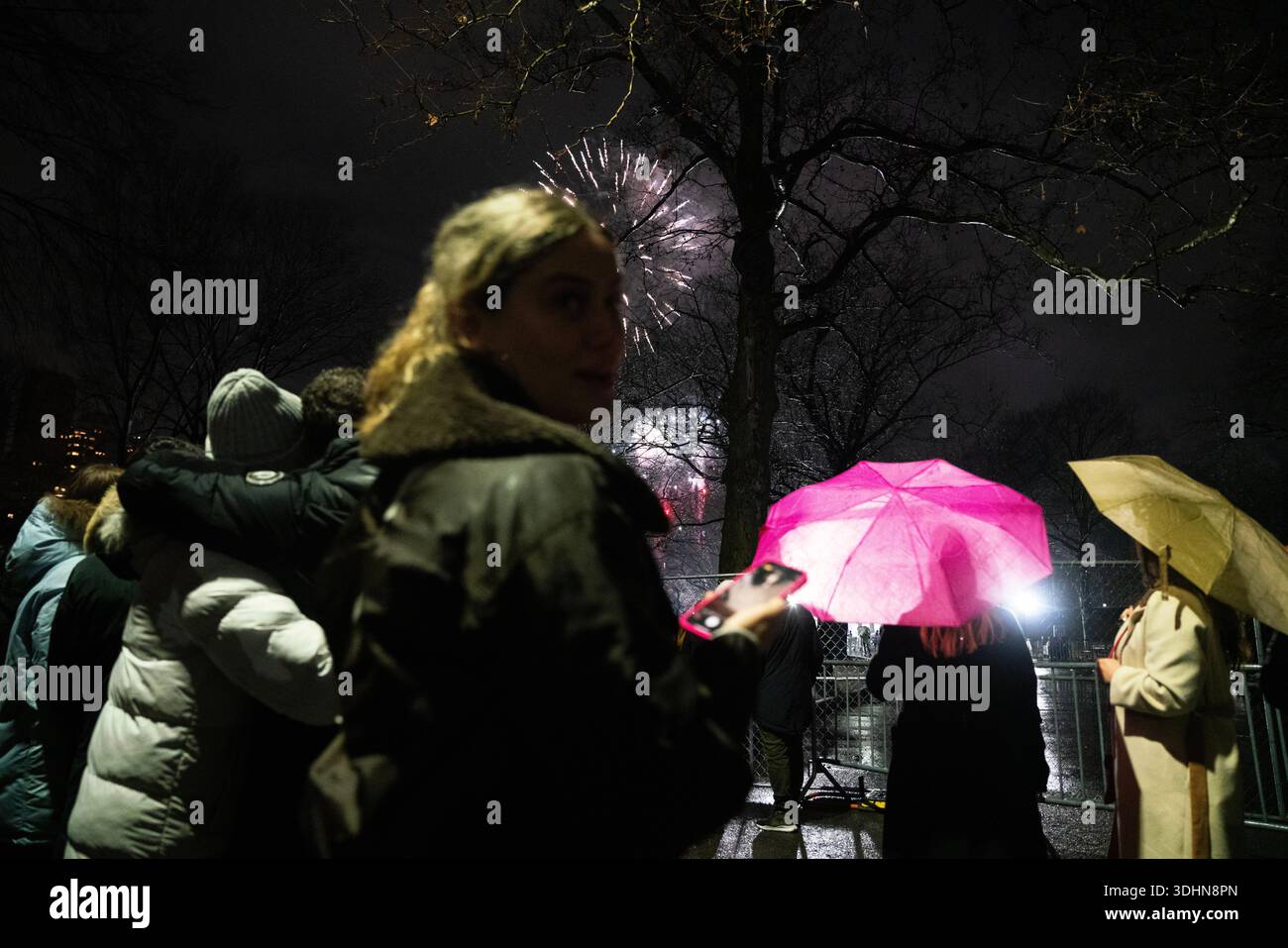 Vivace scena notturna di persone che si godono un vivace festival all'aperto con colorate luci fumé rosa e gialle che creano un'atmosfera festosa. Foto Stock