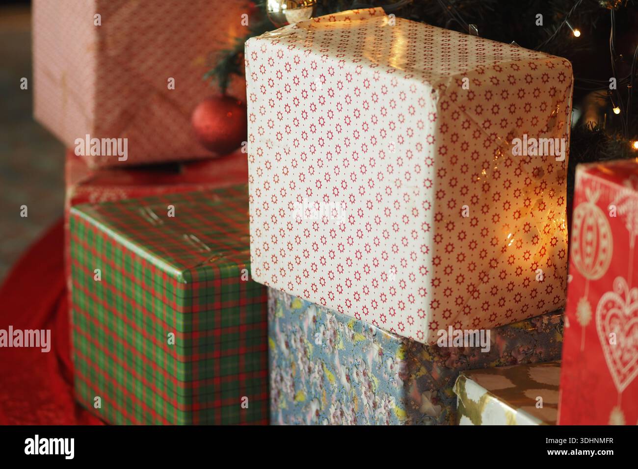 Regali avvolti in carta colorata vicino a un albero di Natale Foto Stock