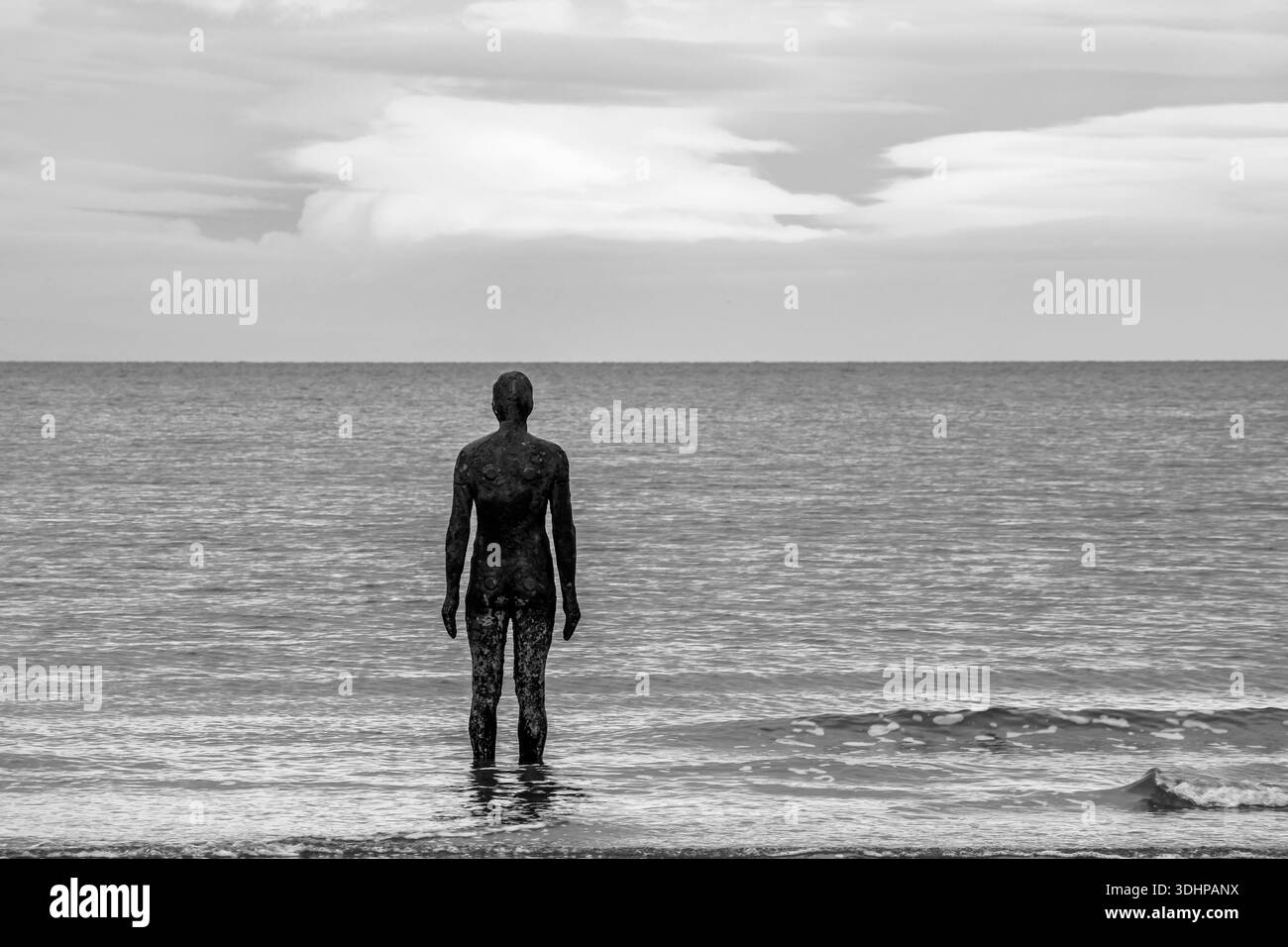 Antony Gormley un altro luogo scultura in piedi in mare a Crosby in bianco e nero Foto Stock