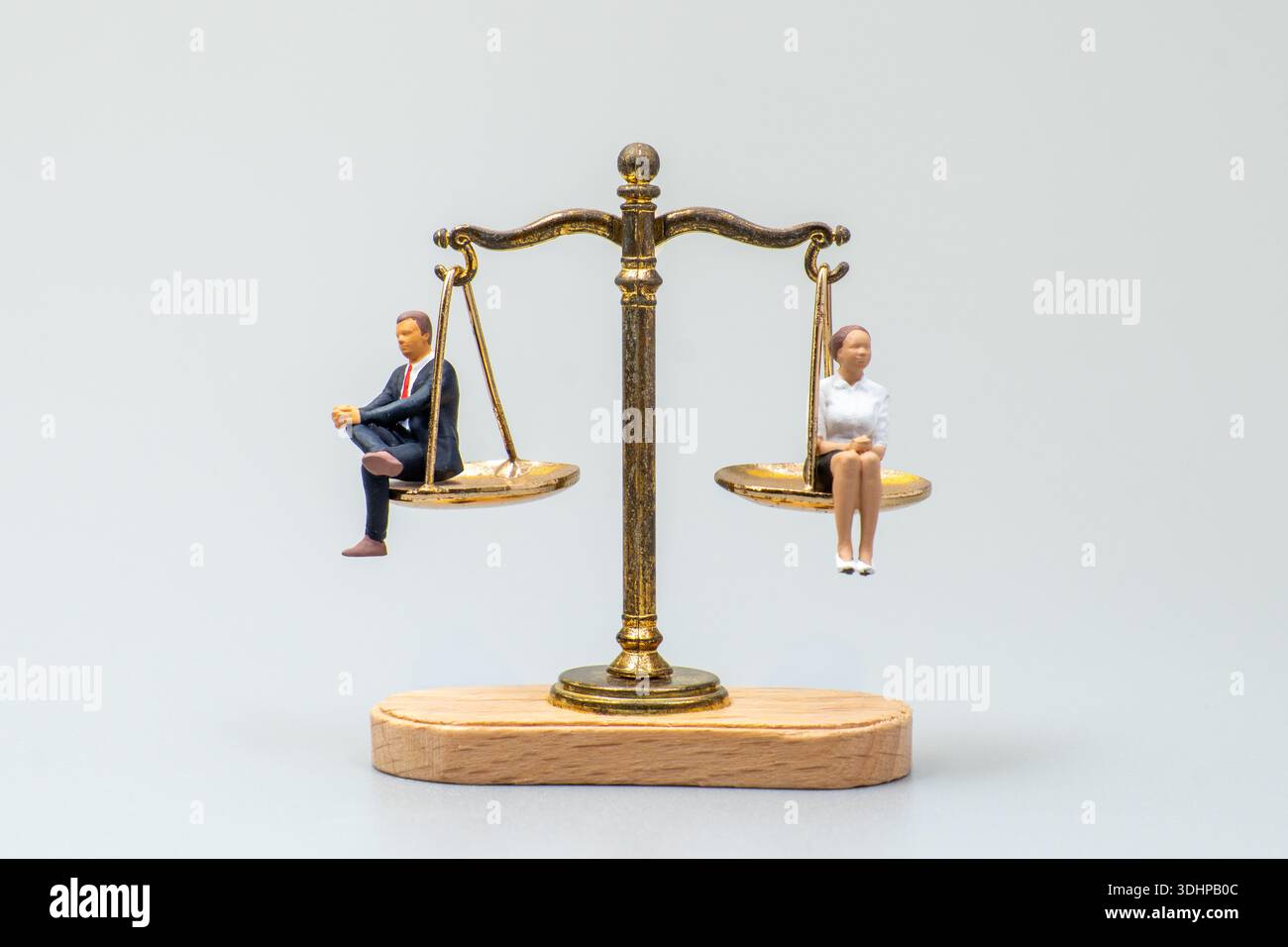 Uomo e donna in miniatura seduti su una scala di equilibrio. Uguaglianza di genere, equità, confronto e concetti di giustizia sociale. Copia spazio per il testo. Foto Stock