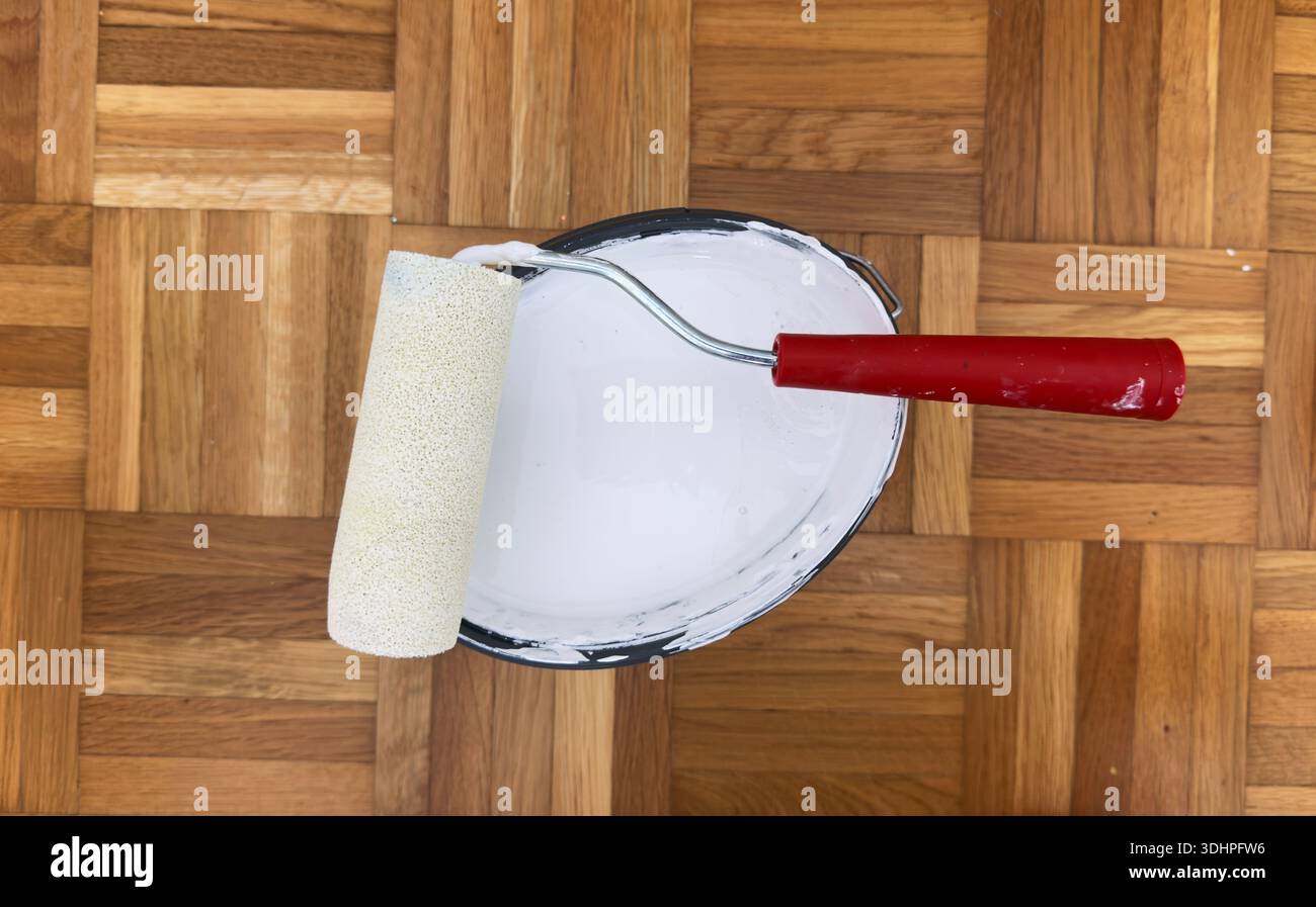 Secchio per utensili per pittura con rullo per pittura e nastro di mascheratura preparato per lavori di ristrutturazione di riparazioni domestiche e decorazioni murali Foto Stock