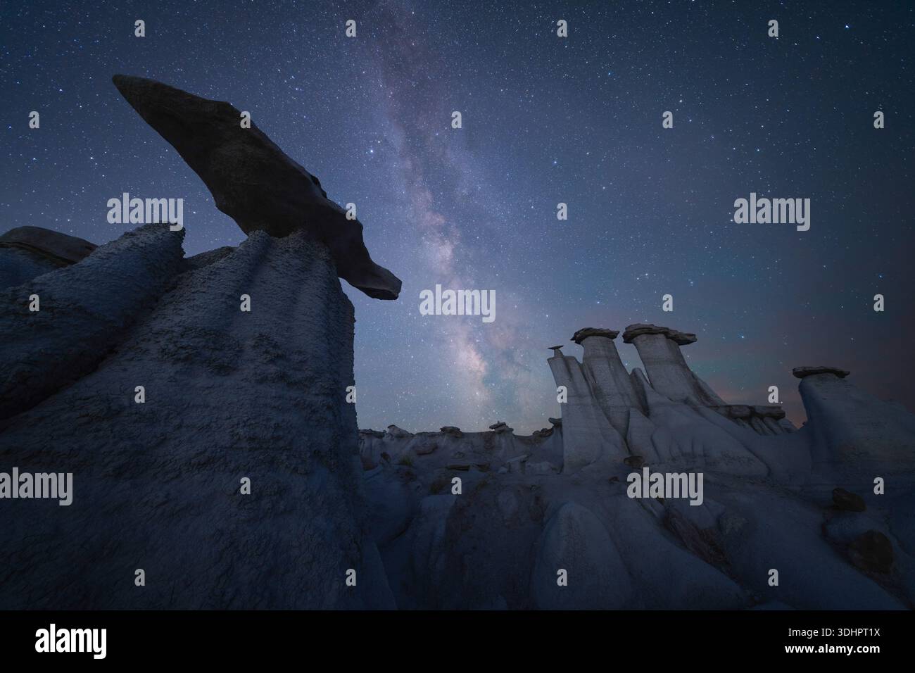 Vista delle formazioni rocciose ultraterrene sullo sfondo della galassia della via Lattea, bagnata dalla luce eterea delle stelle, che creano un paesaggio surreale, Bisti Bad Foto Stock