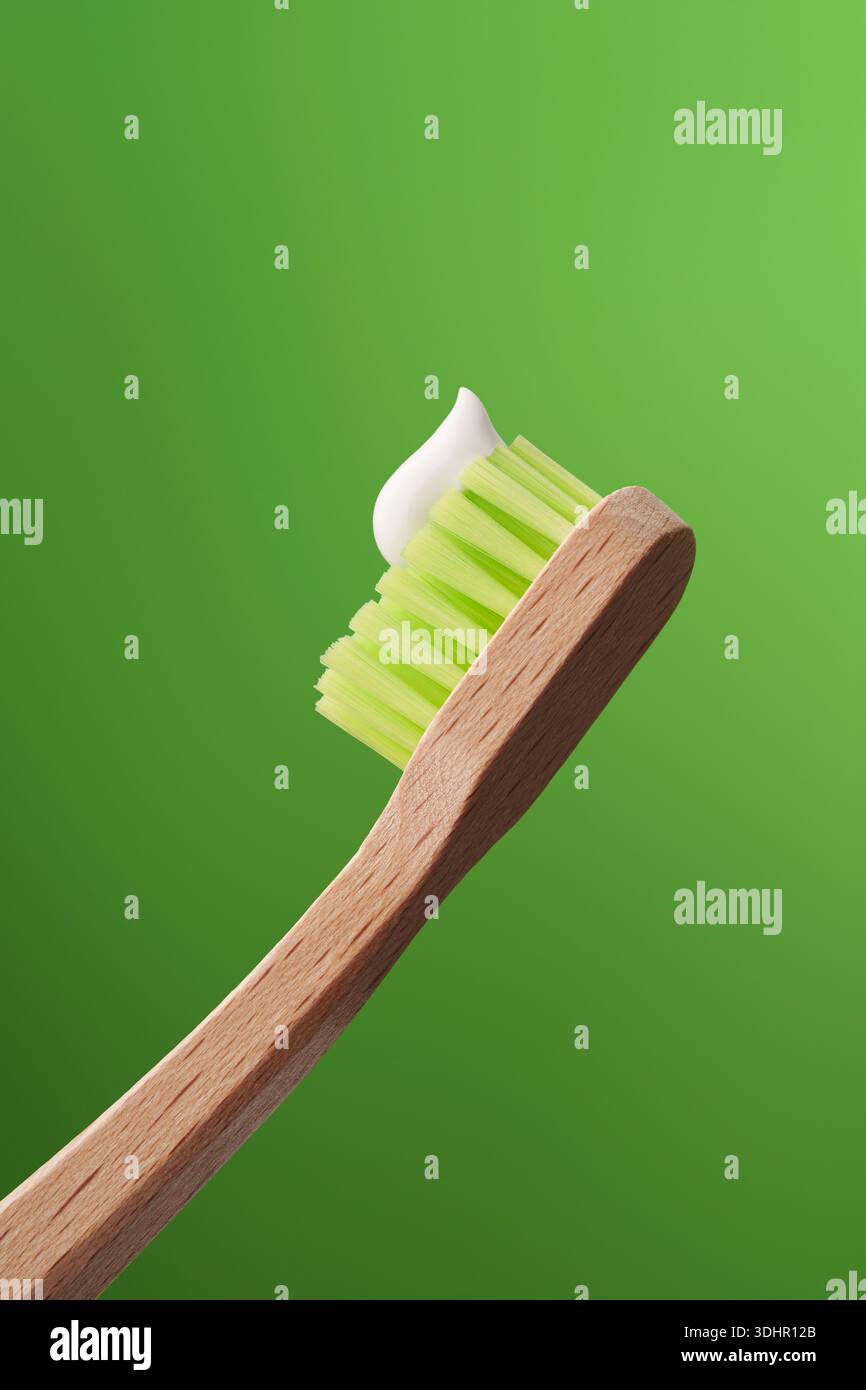 Spazzolino ecologico in bambù con dentifricio su sfondo verde. Foto Stock