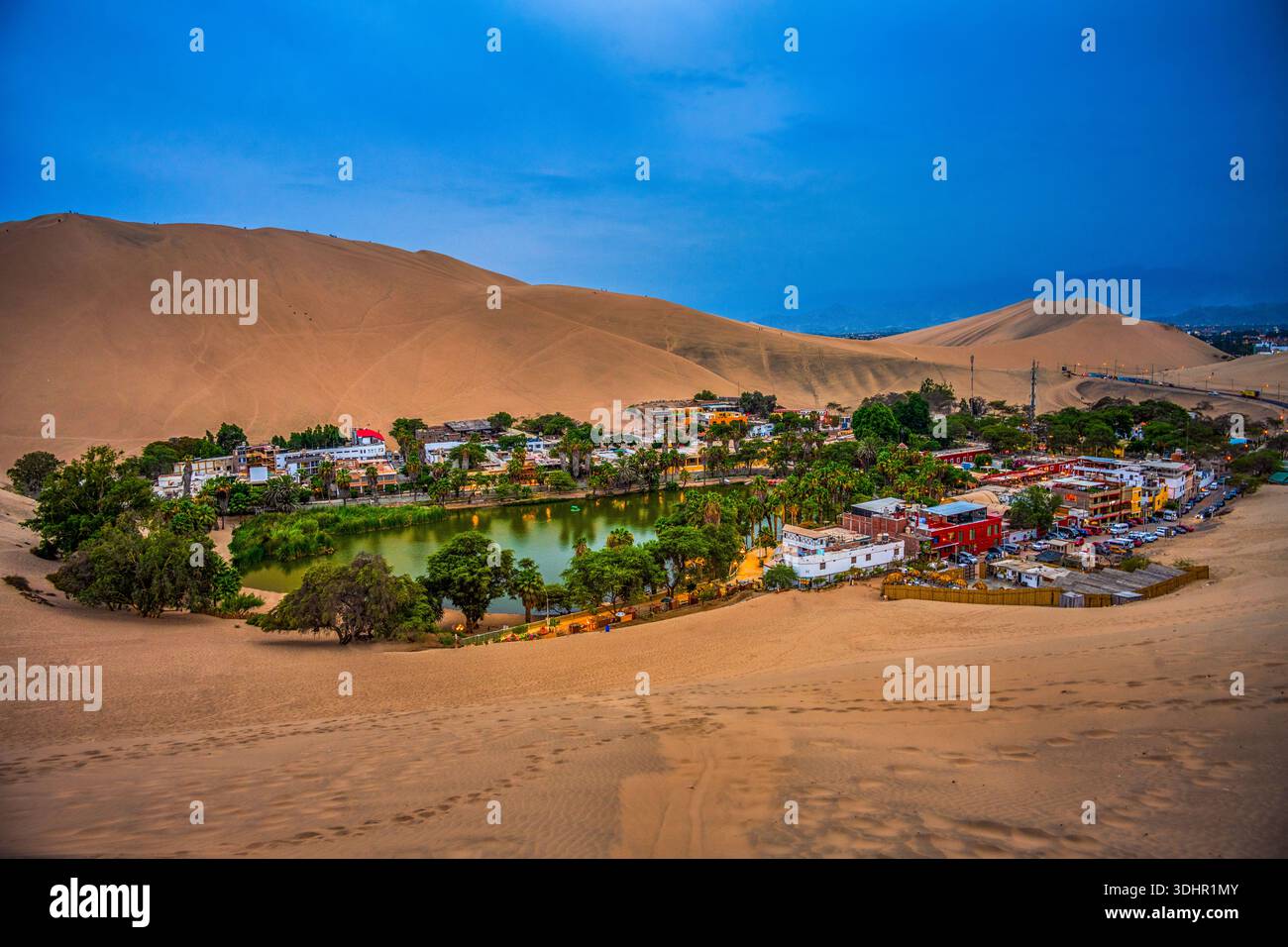 Oasi desertica illuminata di Huacachina al crepuscolo Foto Stock