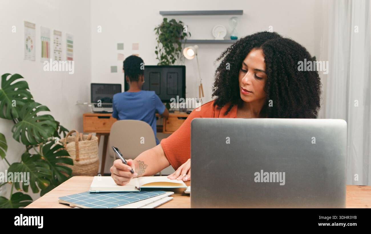 Una donna che lavora con un notebook e scrive in un moderno ufficio Foto Stock