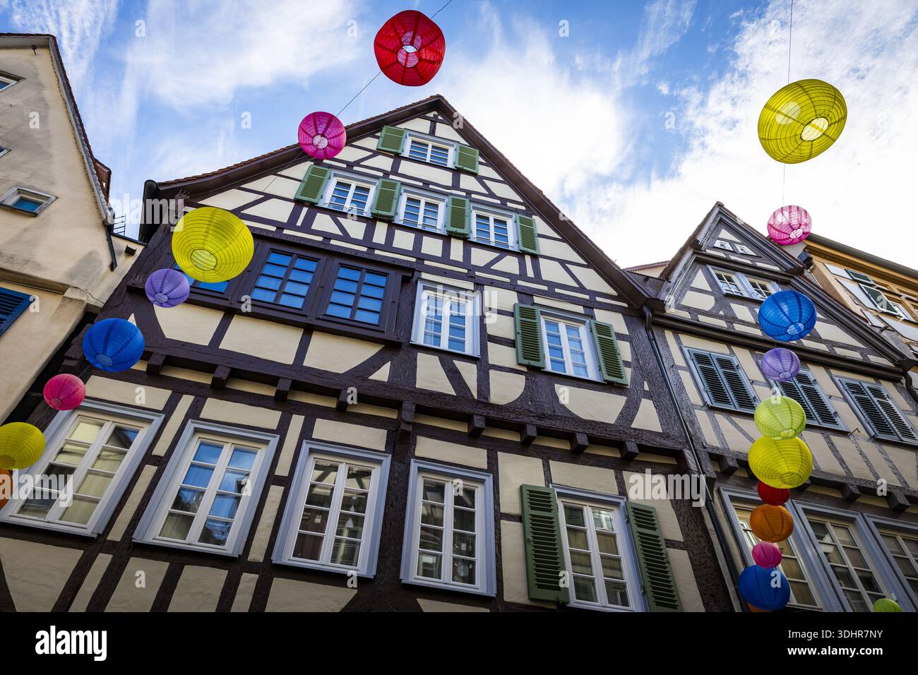 Vista dell'architettura a graticcio adornata da lanterne colorate e vivaci sotto un cielo blu brillante, Tübingen, Baden-Württemberg, Germania. Foto Stock
